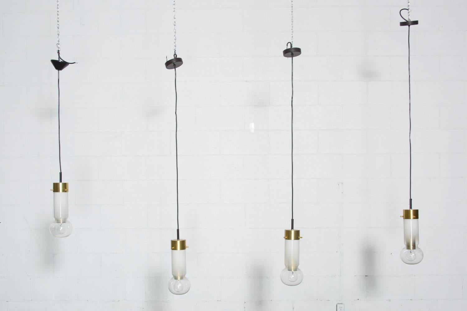 Blown glass drops with opaque neck and transparent orb and brass toned aluminum hardware. In good original condition.