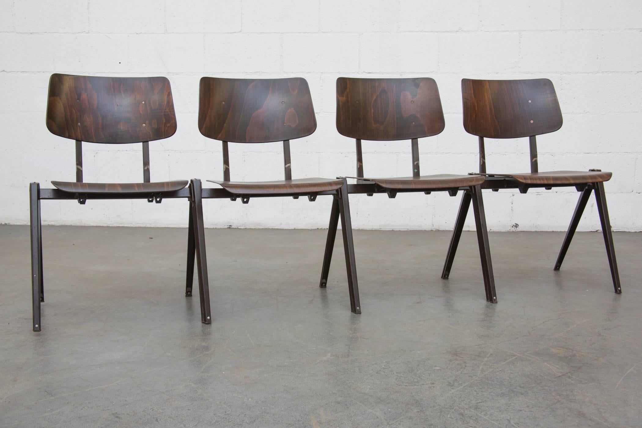 Wenge toned seat and back stacking chairs with brown enameled folded sheet metal prouvé style legs. Legs stack over each other to create a row. Slight variations in color and grain. Original condition with visible wear to enamel on frame. Set price.