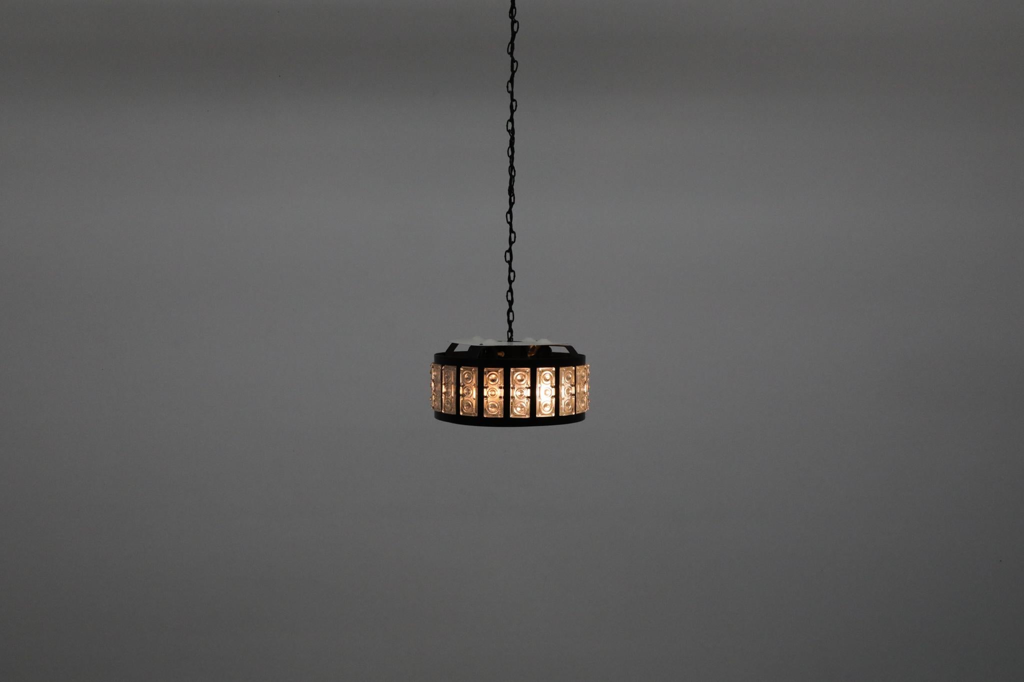 Lampadario svedese di metà secolo con una scultorea struttura in metallo smaltato nero e pannelli in vetro stampato, che ricordano le opere di Erik Höglund o Carl Fagerlund. Un diffusore interno smerigliato ammorbidisce la luce, offrendo una luce
