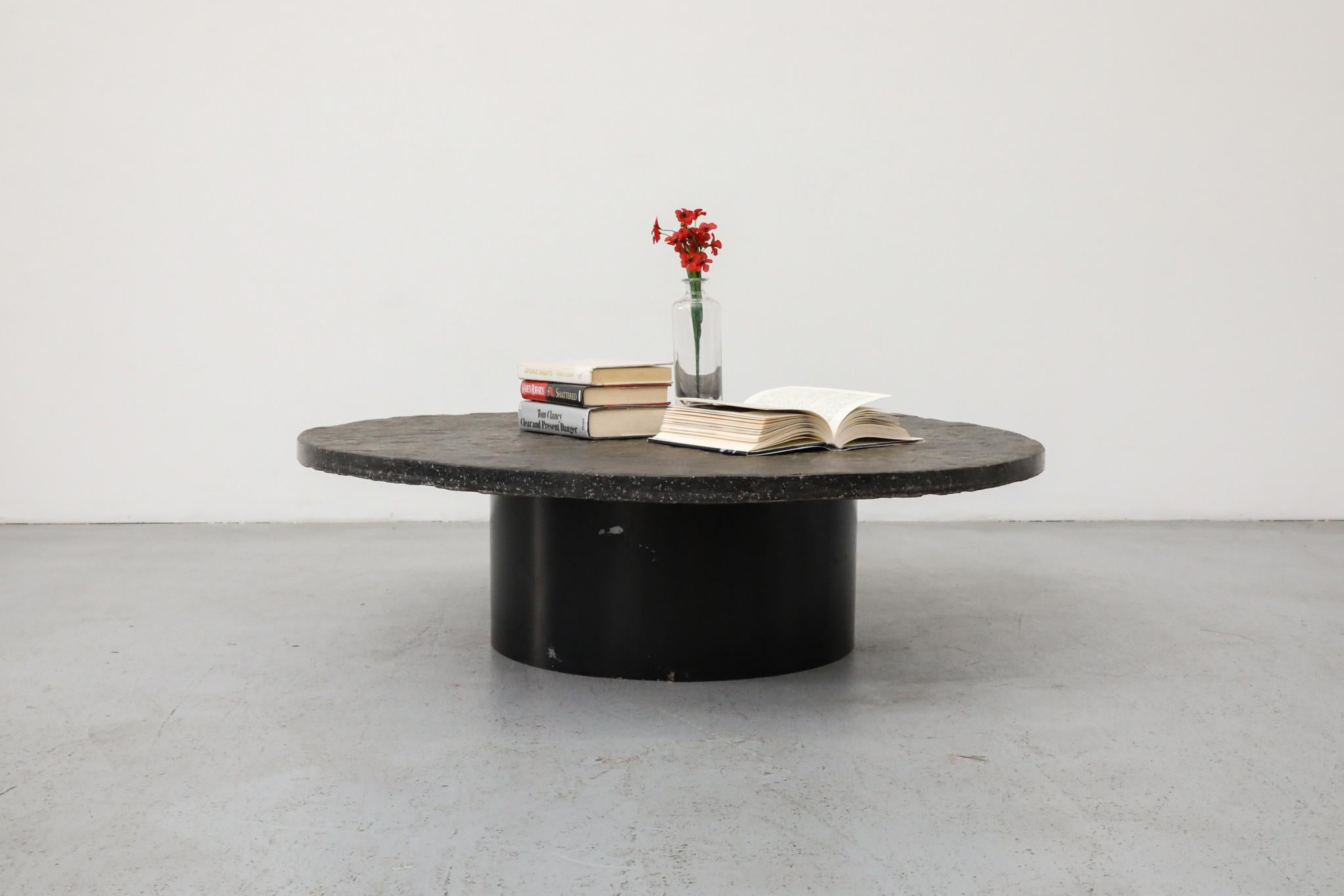 A bold and weighty Brutalist coffee table featuring a thick, 1.5-inch round stone top with an expressive, naturally textured surface. Slightly oversized in diameter compared to many Brutalist-style tables, it offers a commanding presence without
