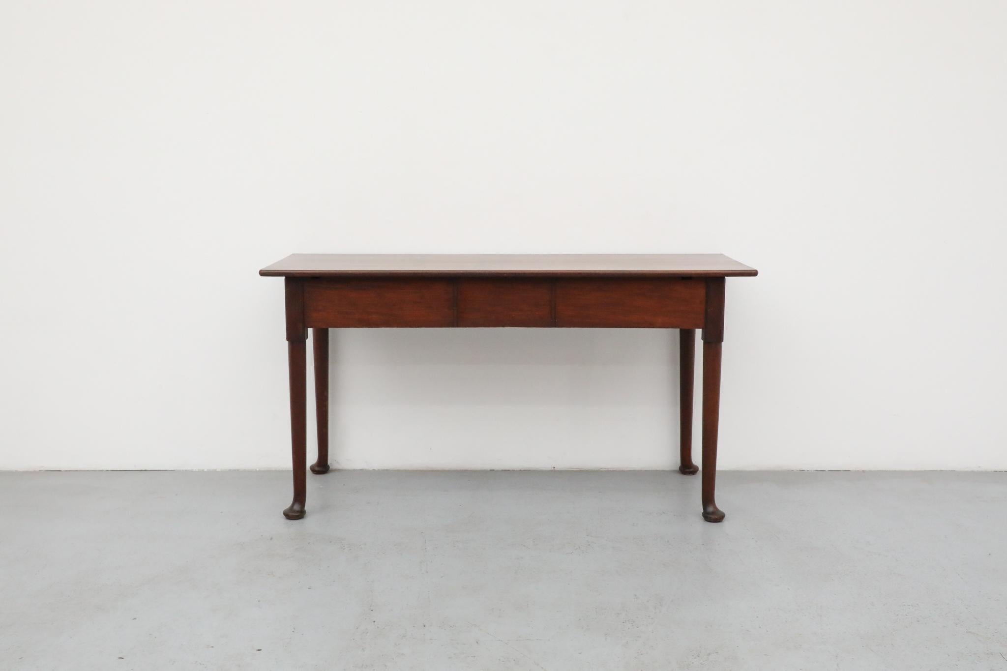 An expressive Amsterdam School entry or console table, crafted from solid mahogany, showcases distinctly curved feet and a robust form that embodies the era's unique artistic spirit. This striking table's design speaks to a period of rich