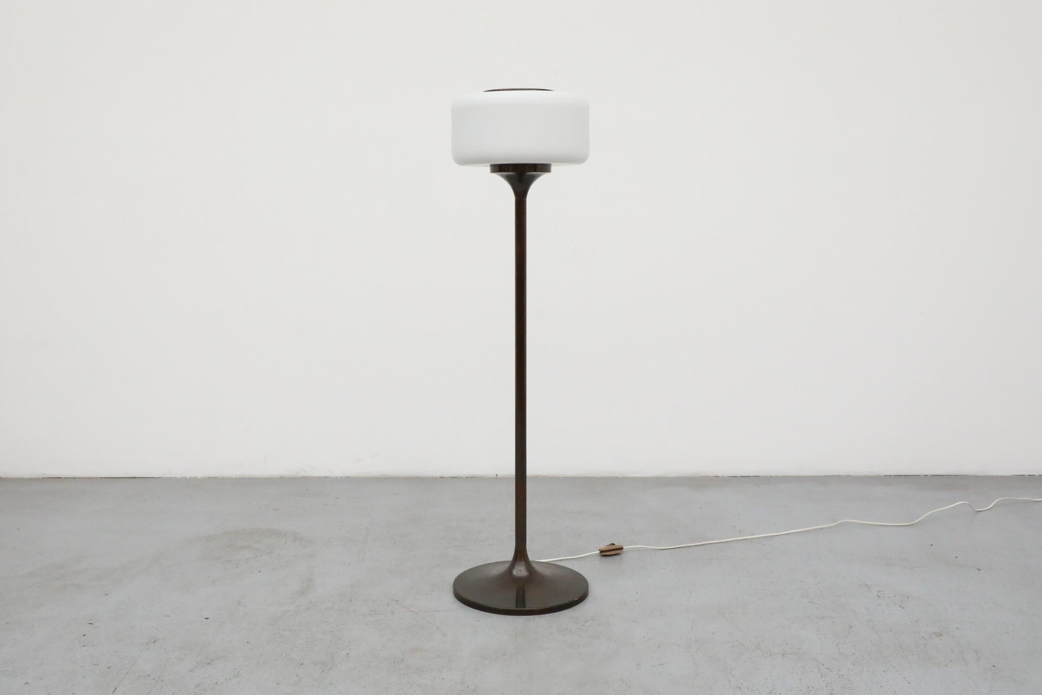 Ce remarquable lampadaire du milieu du siècle est doté d'une finition distinctive en cuivre patiné et d'un abat-jour unique en forme de pilule en verre au lait. Son design évoque l'élégante esthétique moderniste d'Elegos Martinelli et de Martinelli