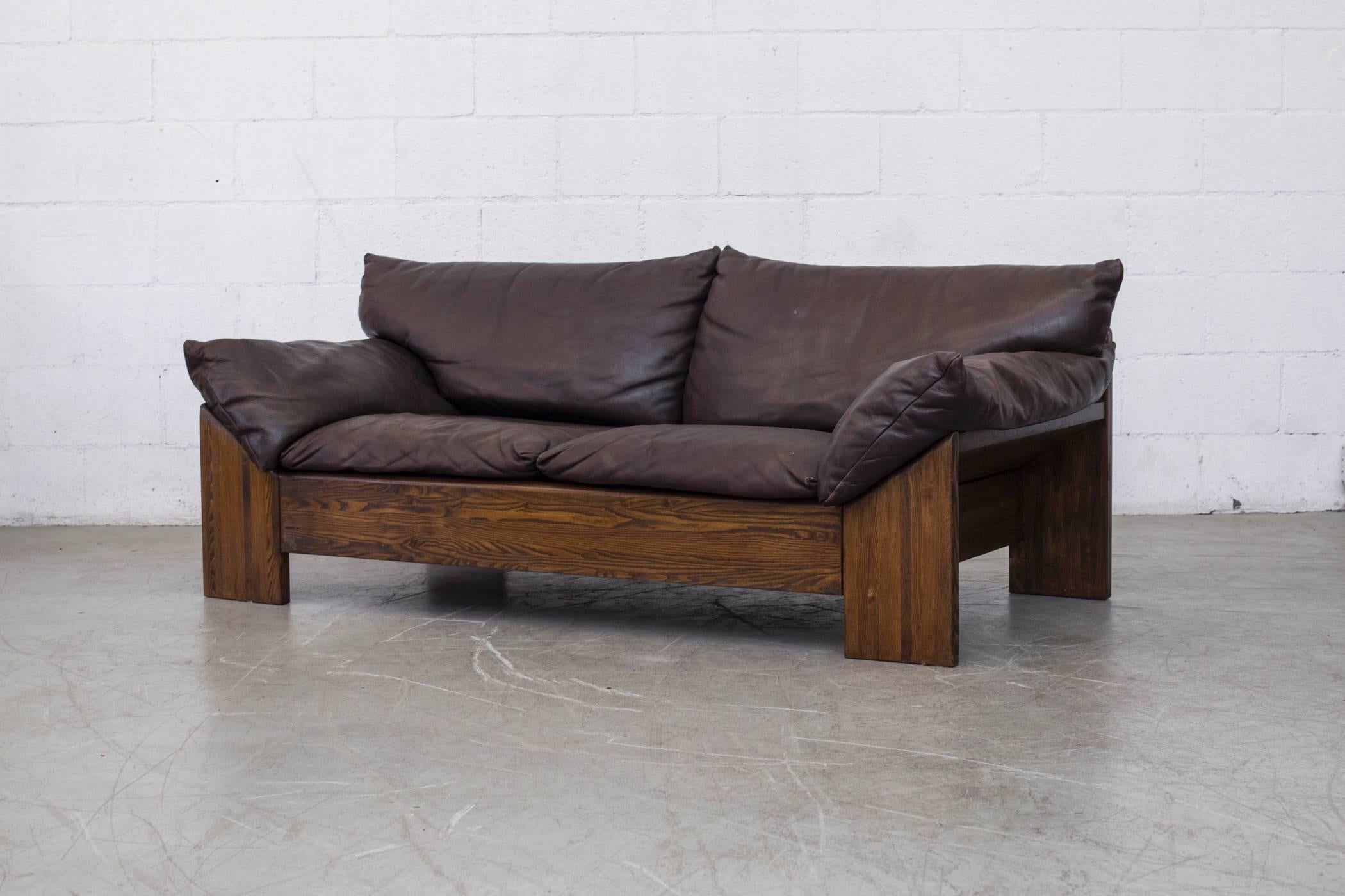 Impressive dark oak loveseat with thick and heavy buffalo leather cushions. Back panel also with leather inset, good original condition with visible patina and wear consistent with it's age and usage. Matching three-seat sofa also available, listed