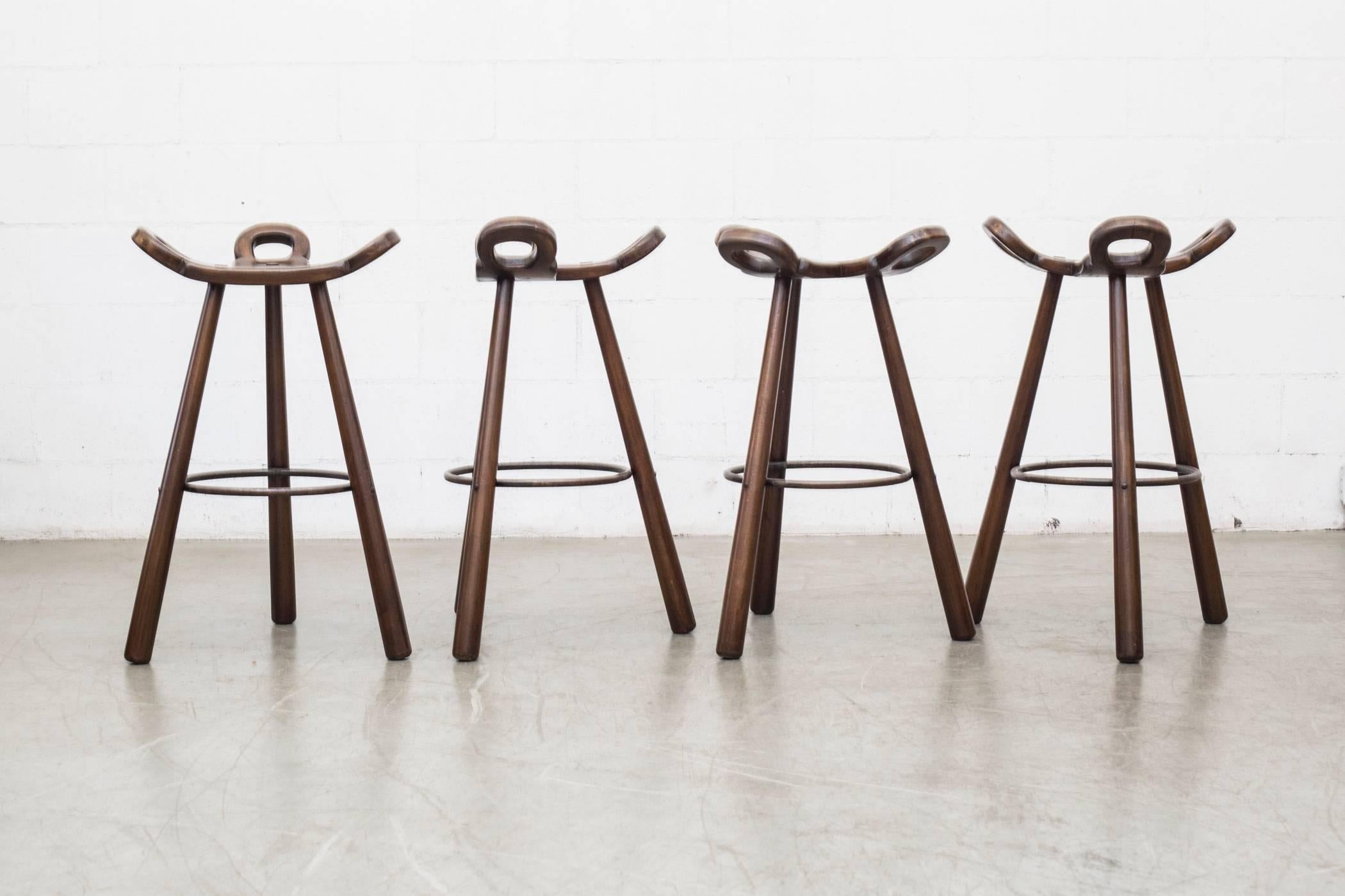 Elegantly carved Brutalist "Marbella" bar stool by Confonorm, Spain, 1970. Cool carved bar stool seat with three legs and iron footrest. Some cracking to the wood. Assorted wood tones. Original condition. Others Available, listed