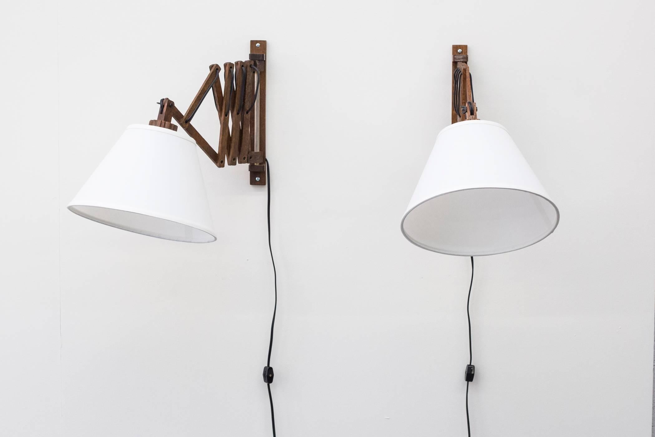 Pair of Mid-Century Modern wood wall-mounted accordion lamps with new conical linen shades. In good original condition with visible signs of age. Set price.