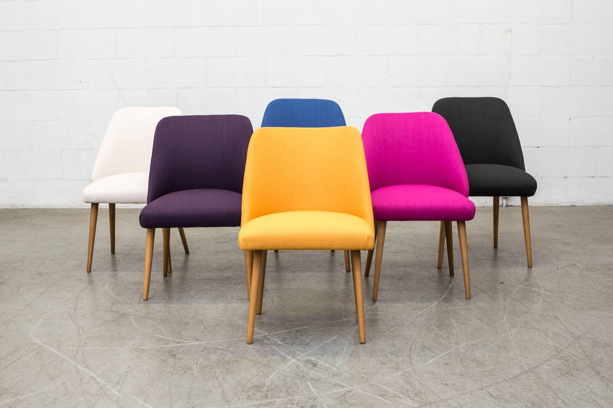 Newly upholstered Mid-Century cocktail chairs. Available in assorted colors. Lightly refinished natural birch tapered legs. Slightly varying sizes and shapes. Two weeks lead time needed for quantities to be re-upholstered. Currently 30 newly