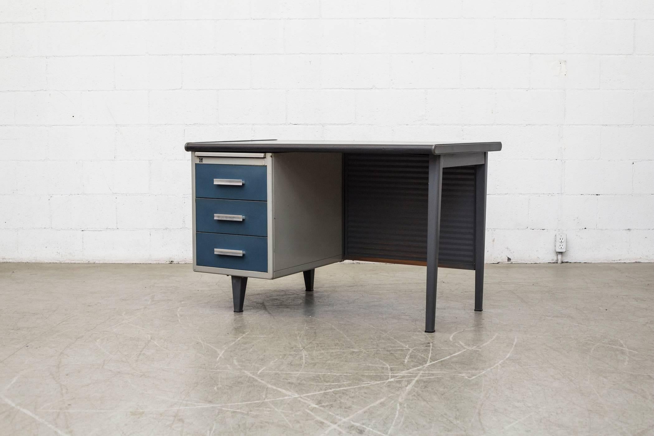 Mid-Century Industrial desk by A.R. Cordemeijer for Gispen. Charcoal linoleum top with three blue left-side drawers and grey frame and pull-out enameled tray. Great corrugated privacy screen in back. Good original condition with visible signs of