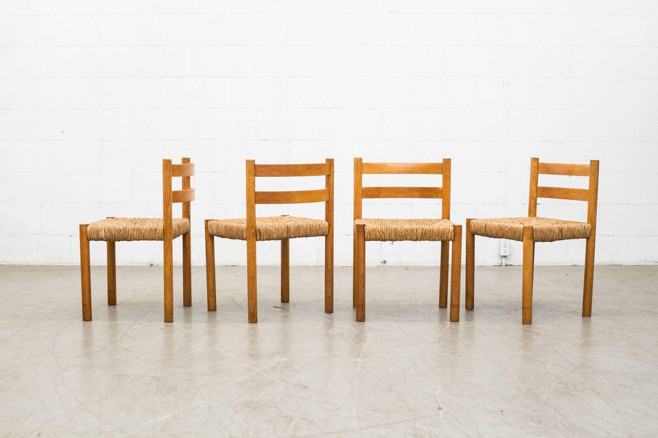 Set of four beautiful Charlotte Perriand style birch dining chairs with elegantly woven rush seats. In original condition with visible signs of wear. Set price.