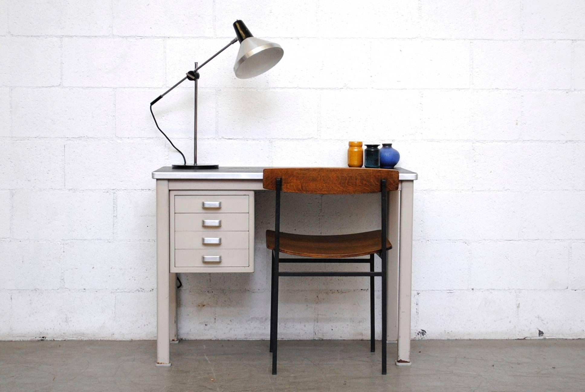 Light grey industrial metal office desk. 4 drawers with brushed chrome hand pulls. Original black linoleum top. In very original condition with wear consistent with its age and usage.