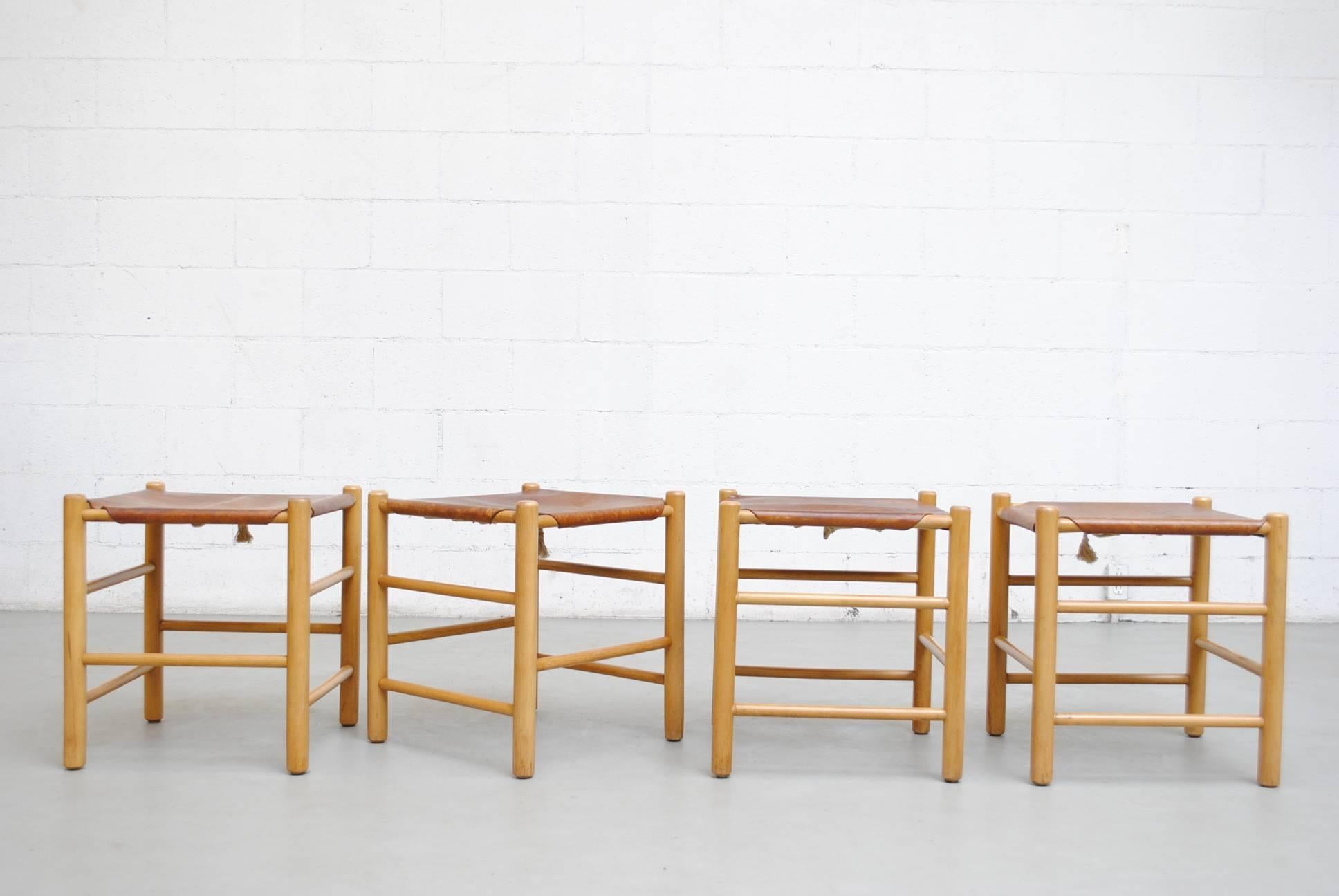 Four beautiful Charlotte Perriand style birch stools with natural leather seats. Visible wear and patina to the leather. Wood in original condition with wear consistent with their age and usage.