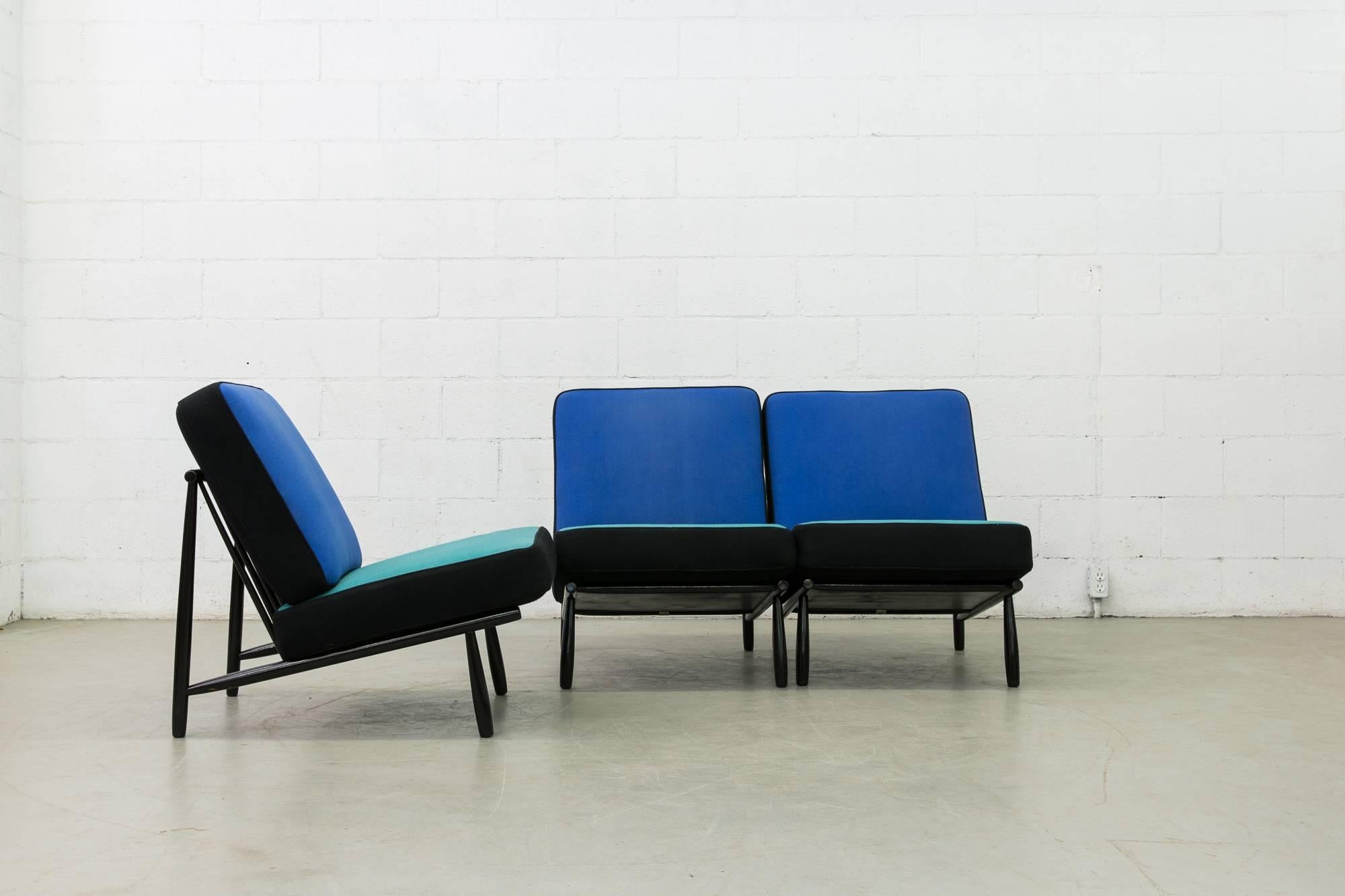Designed in 1955 for the Helsingborg Expo this is a set of three black lacquered wood framed easy chairs with royal/turquoise/black wool upholstered cushions. The chairs sit low to the ground and can be used as a three-seat sofa, or three individual