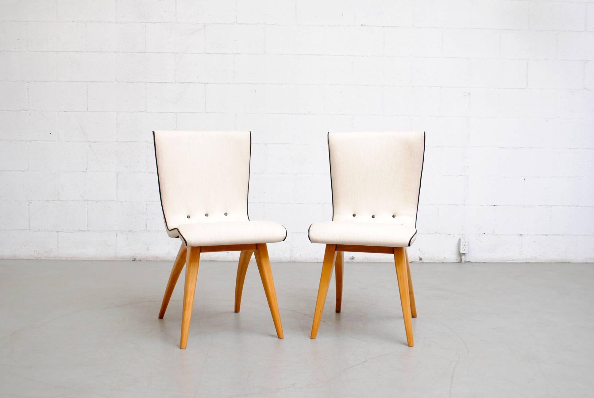 Beautiful swooping upholstered dining chairs by Van Os in new bone white upholstery with black piping and accent buttons. Gorgeous lightly refinished curved natural wood legs. Set price.
 