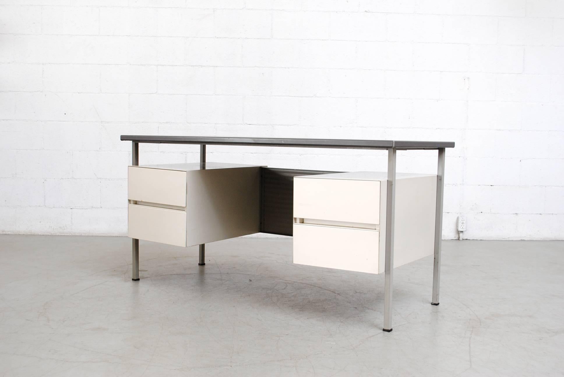 Floating grey vinyl topped Industrial desk with pale grey enameled metal frame and privacy screen with white enameled double drawers. Good original condition with visible wear consistent with its age and usage.