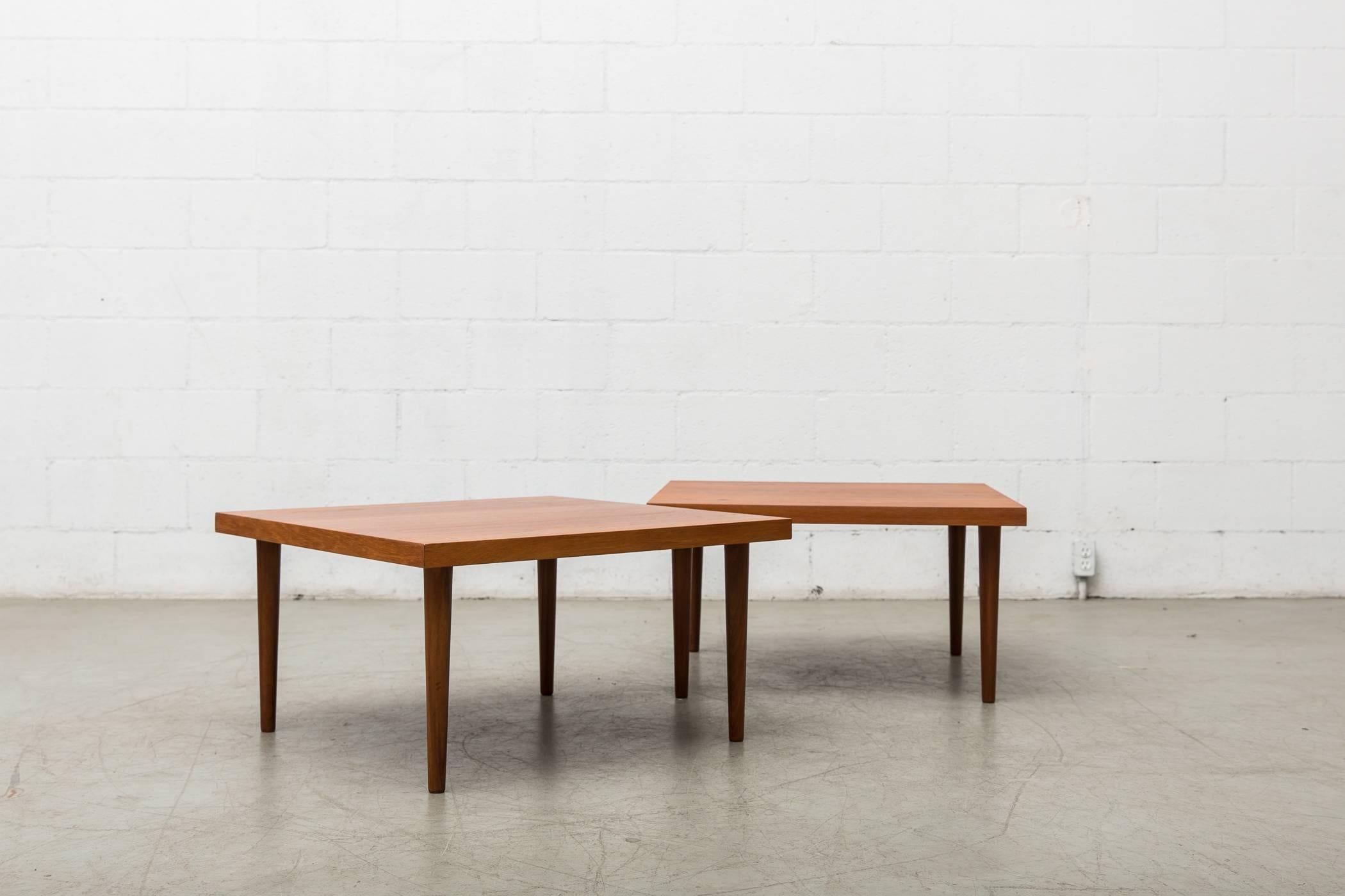 Matching pair of simplistic Mid-Century square teak coffee tables with round legs. Good original condition, nice grain pattern on each table. Set price.
