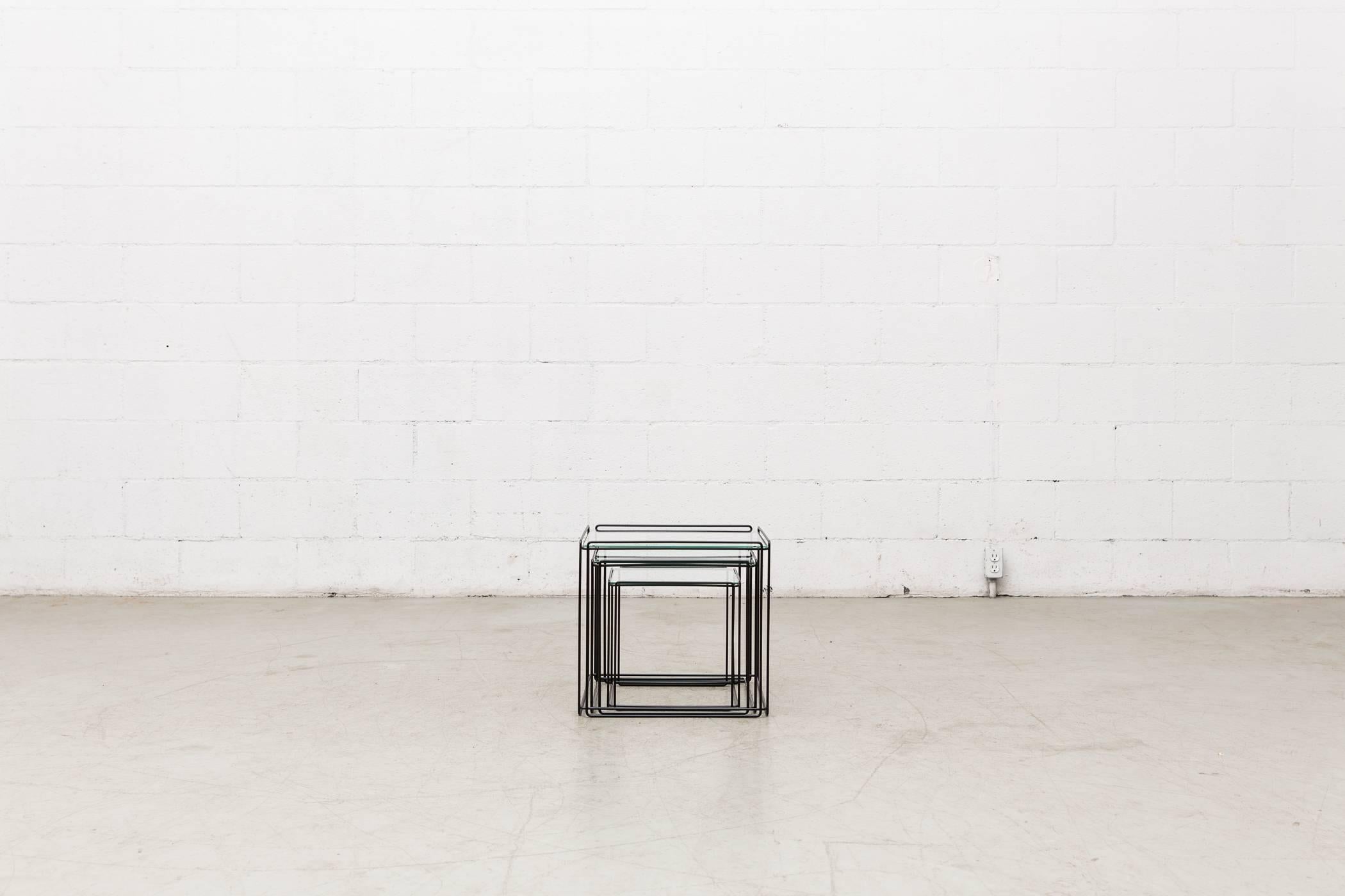 Set of three small glass nesting side tables with black enameled metal wire frames. In original condition

Measurements: 
Large - 17 x 17 x 17 
Medium - 15 x 15 x 15 
Small - 12 x 12 x 12.