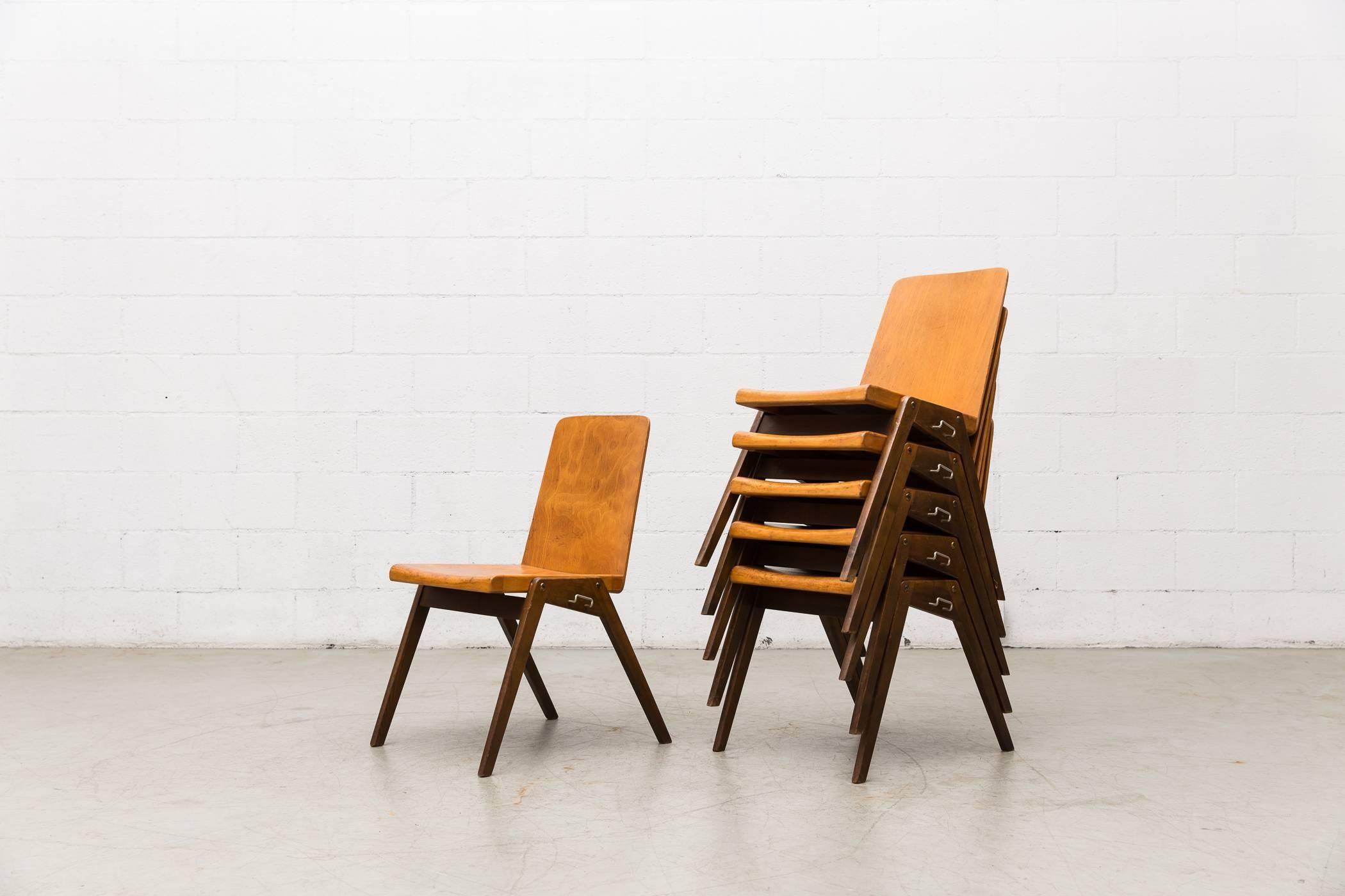 Gorgeous Roland Rainer style stacking school chairs. Light natural wood seats and chocolate wood legs. Hooks on sides used to connect chairs for group/bench seating. Original condition.