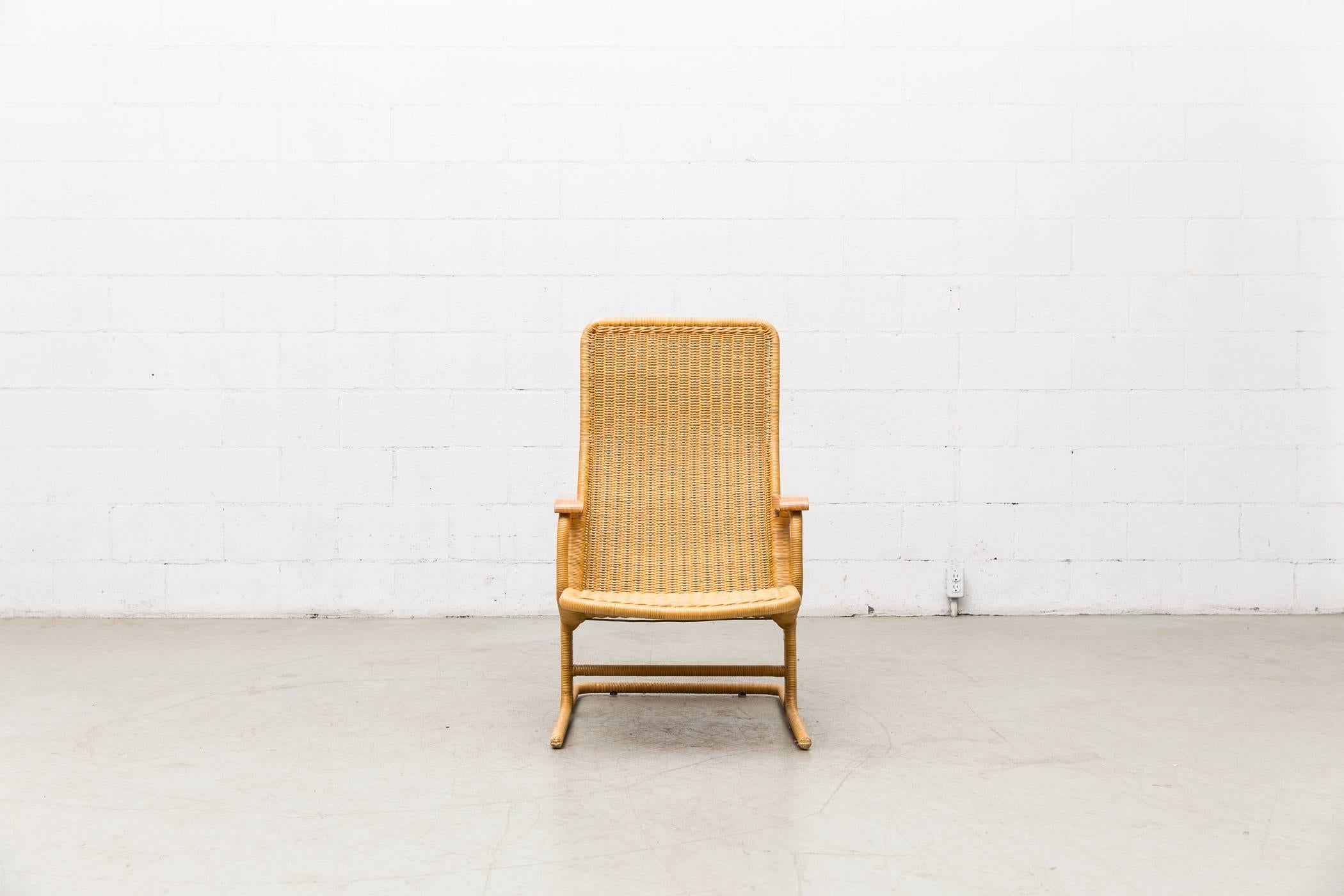 Elegantly woven Dirk Van Sliedregt rattan high-back lounge chair with natural wood arms. Tubular metal frame wrapped in bamboo. Good original condition with minimal rattan breakage. Similar styles available listed separately.