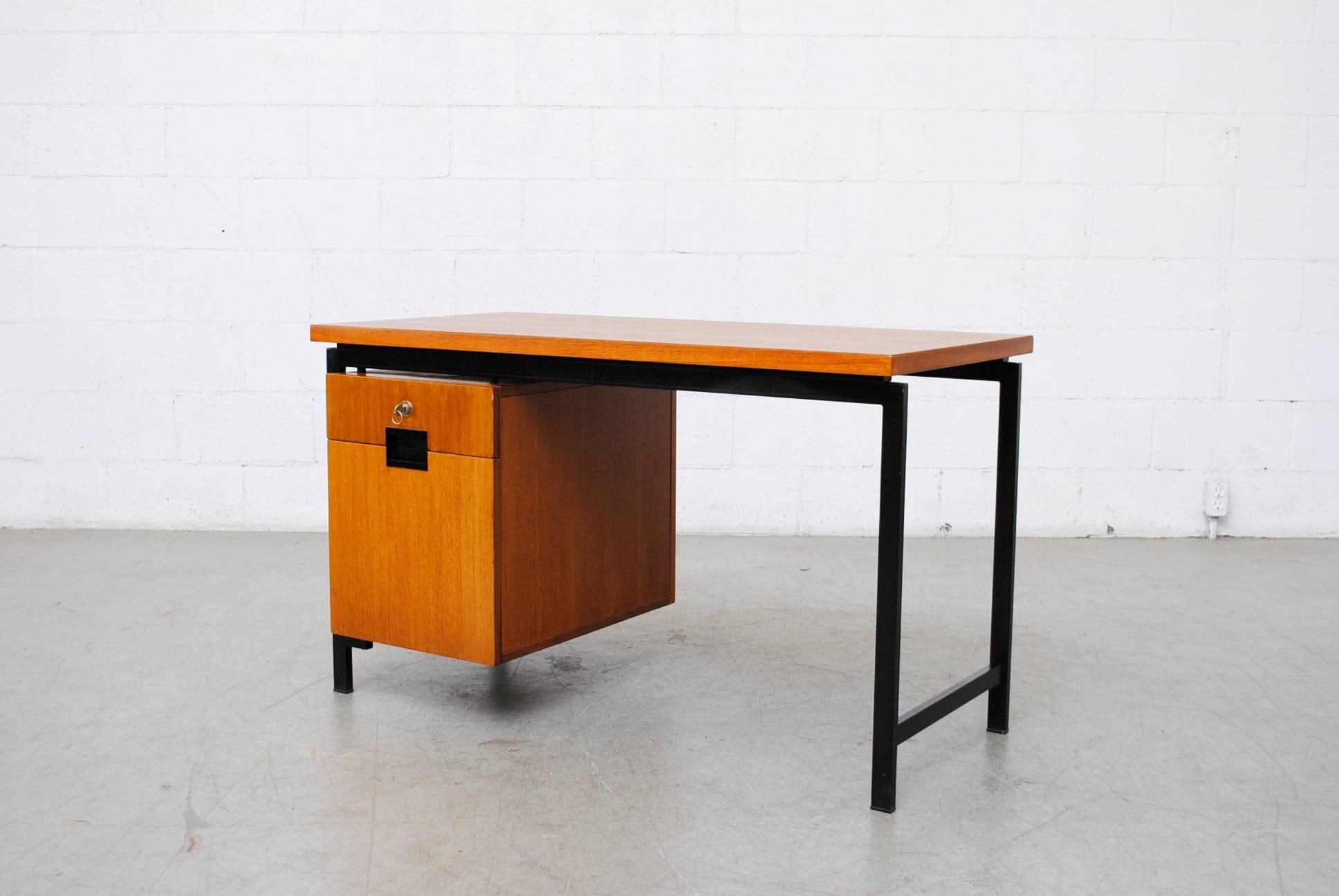 Small version writing desk in golden teak with top drawer and rare file drawer. Signature curved drawer interior. Acrylic molded drawer pulls. Left side console. In good original condition with wear consistent with its age.