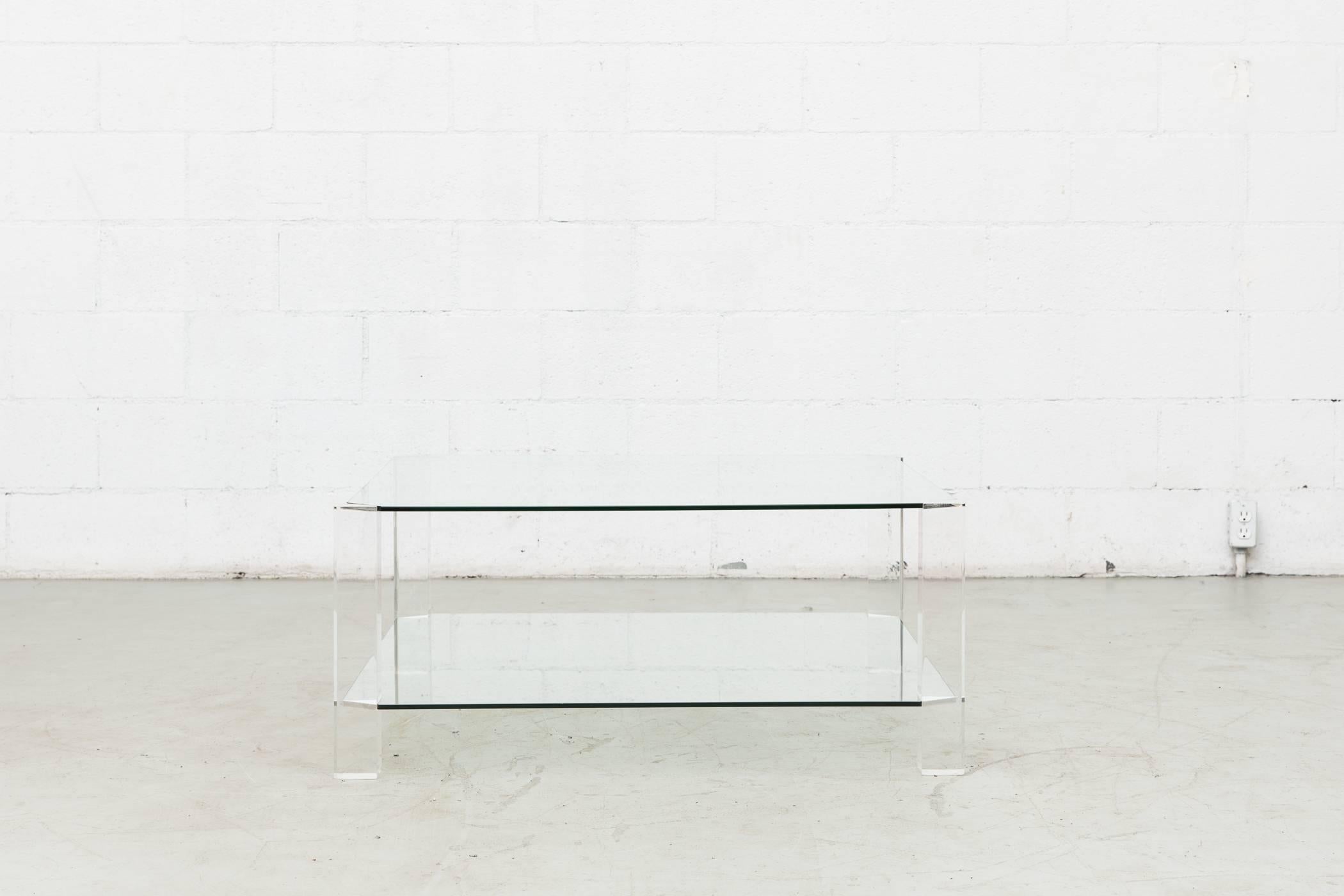 Beautiful two-tiered glass coffee table with four clear Lucite legs. Ultra chic, original condition with visible wear to glass and Lucite frame.