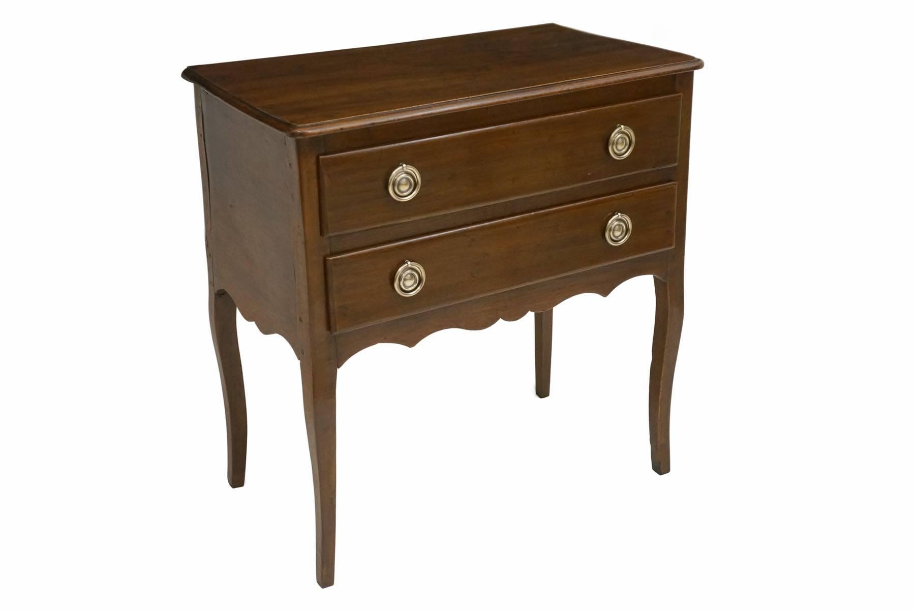 Walnut two drawer commode with shaped apron and brass handles.