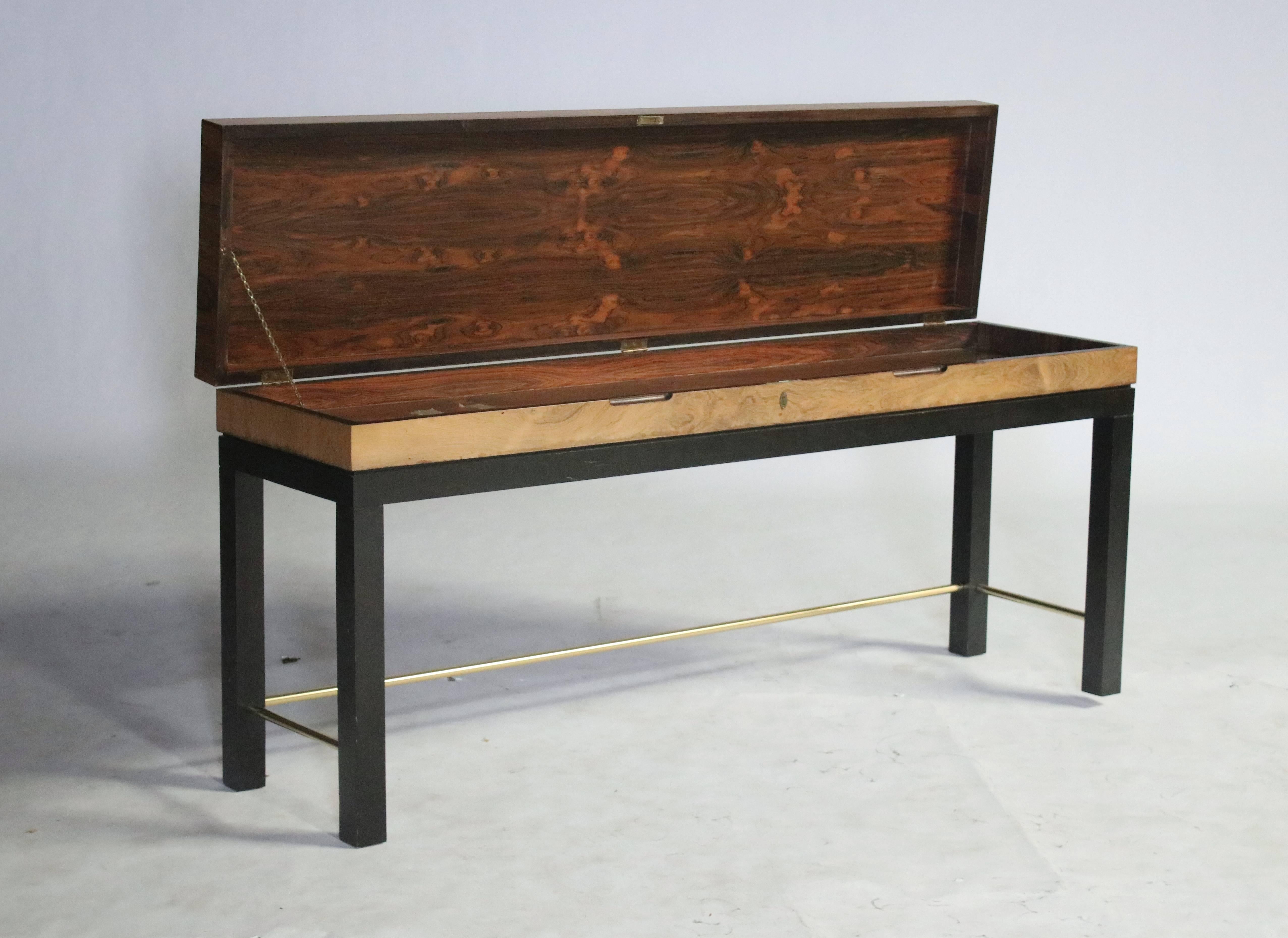 Rosewood console table opens to a sword chest with a beautiful rosewood interior. Chest sits on a parsons style ebony wood frame with brass stretchers in the style of Edward Wormley for Dunbar.