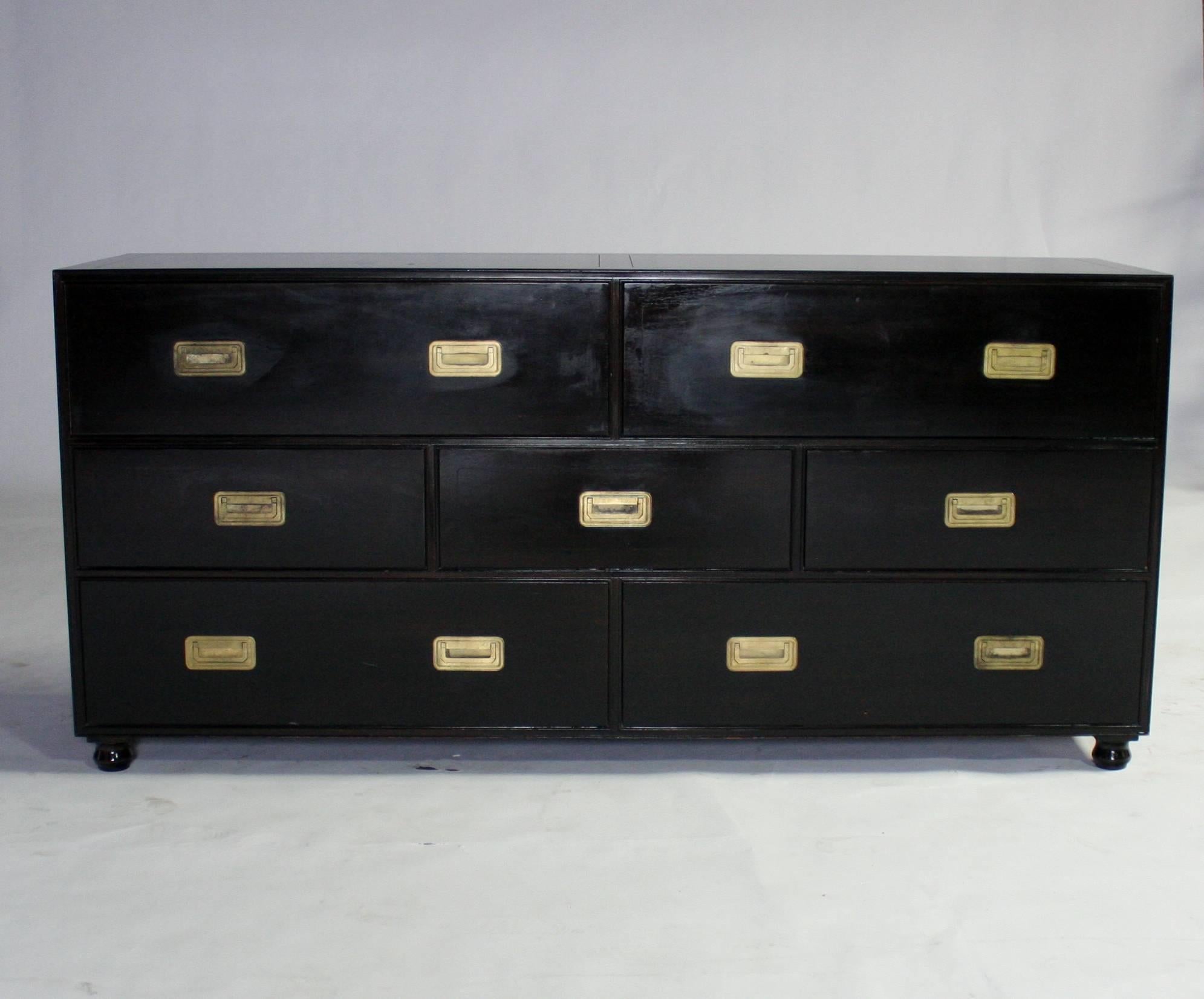 Handsome black lacquered Baker Campaign style dresser featuring seven drawers with elegant recessed brass pulls and ball-shaped feet. All drawers open smoothly and are clean. Metal label inside top drawer.