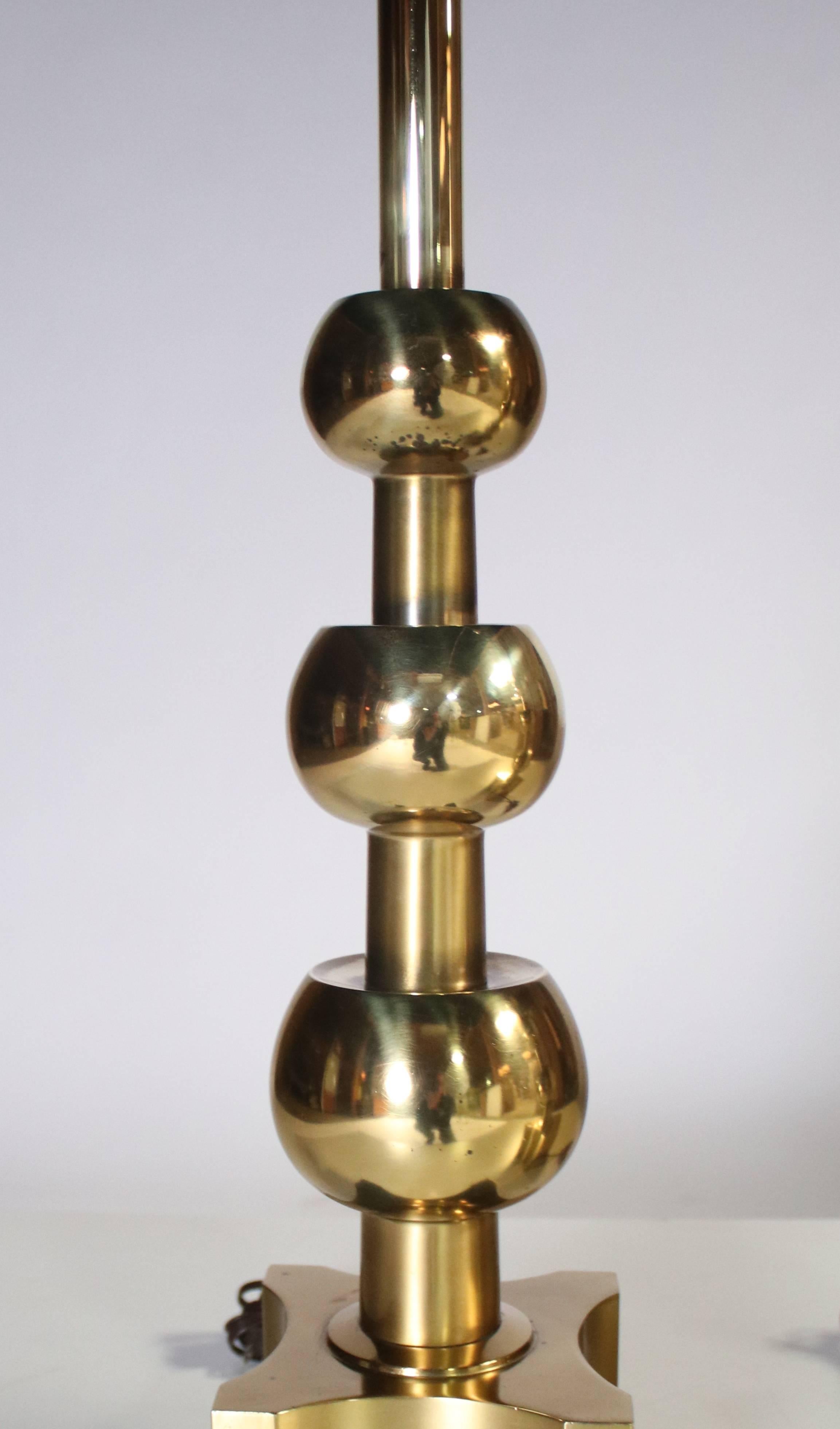 Pair of brass "stacked orb" or "graduated ball" table lamps in the style of Tommi Parzinger for Stiffel, Labelled. Wired and in working condition. These lamps have been polished to a clean shine.