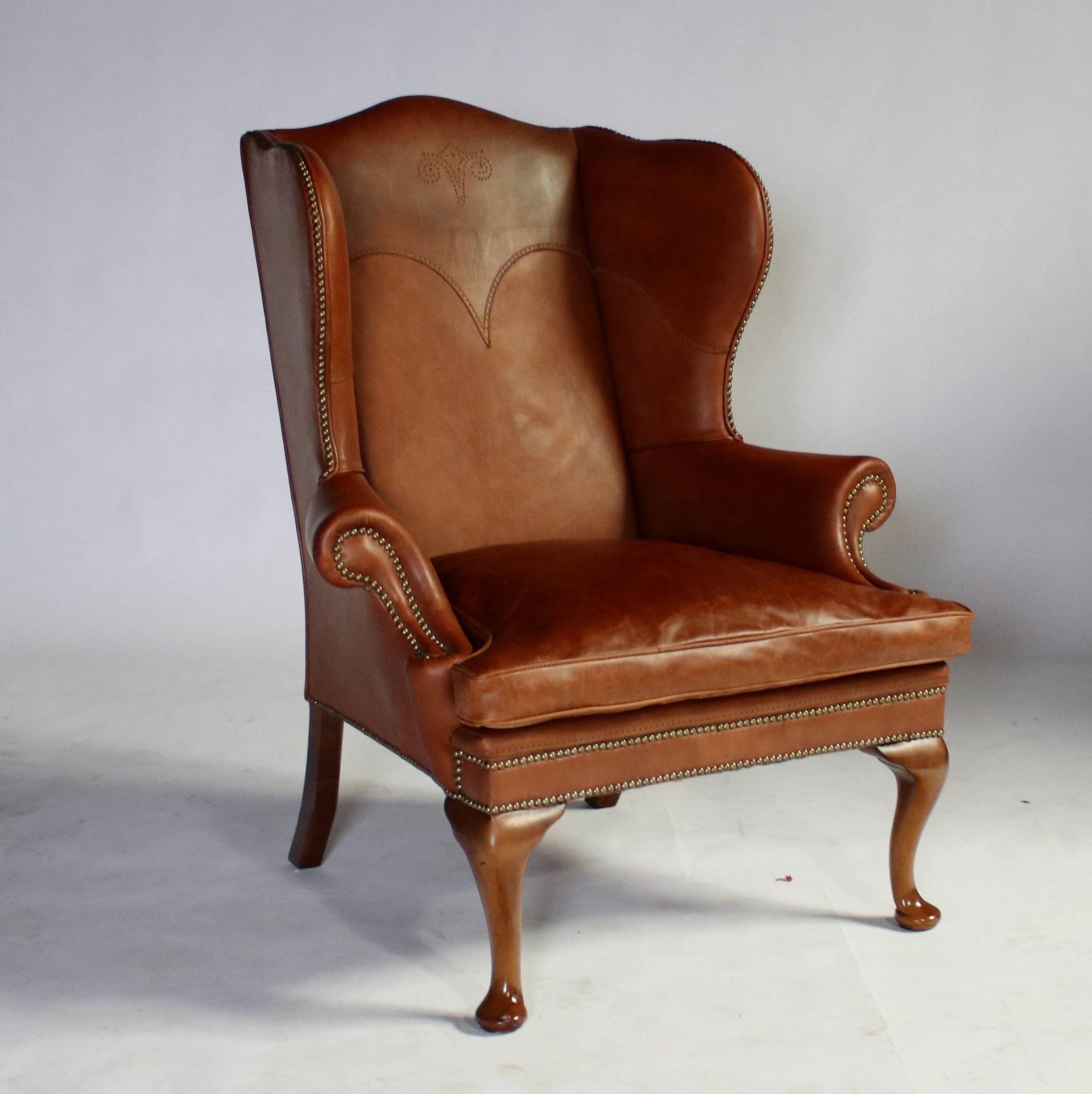 George I style wingback leather chair by Ralph Lauren with cabriolet walnut legs and nailheads throughout. A western-style embroidered stitch makes this 1980s example truly unique from some of the earliest furniture pieces by Ralph Lauren. The