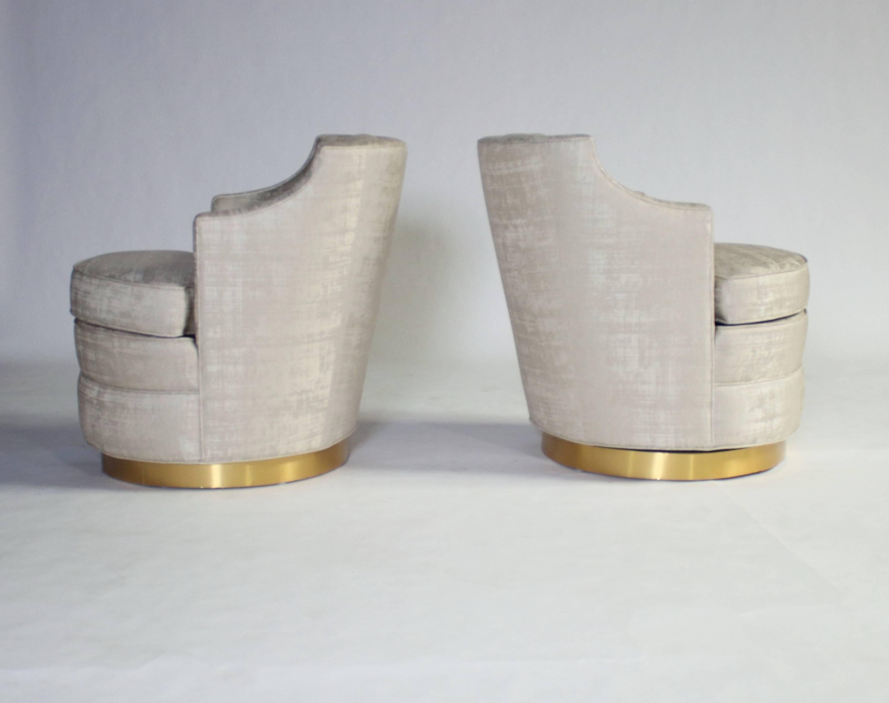 Lovely pair of swivel chairs by Edward Wormley for Dunbar reupholstered in a champagne color fabric with a subtle silvery shimmer. All newly reinvented with brushed gold bases. Swivels 360 degrees smoothly.