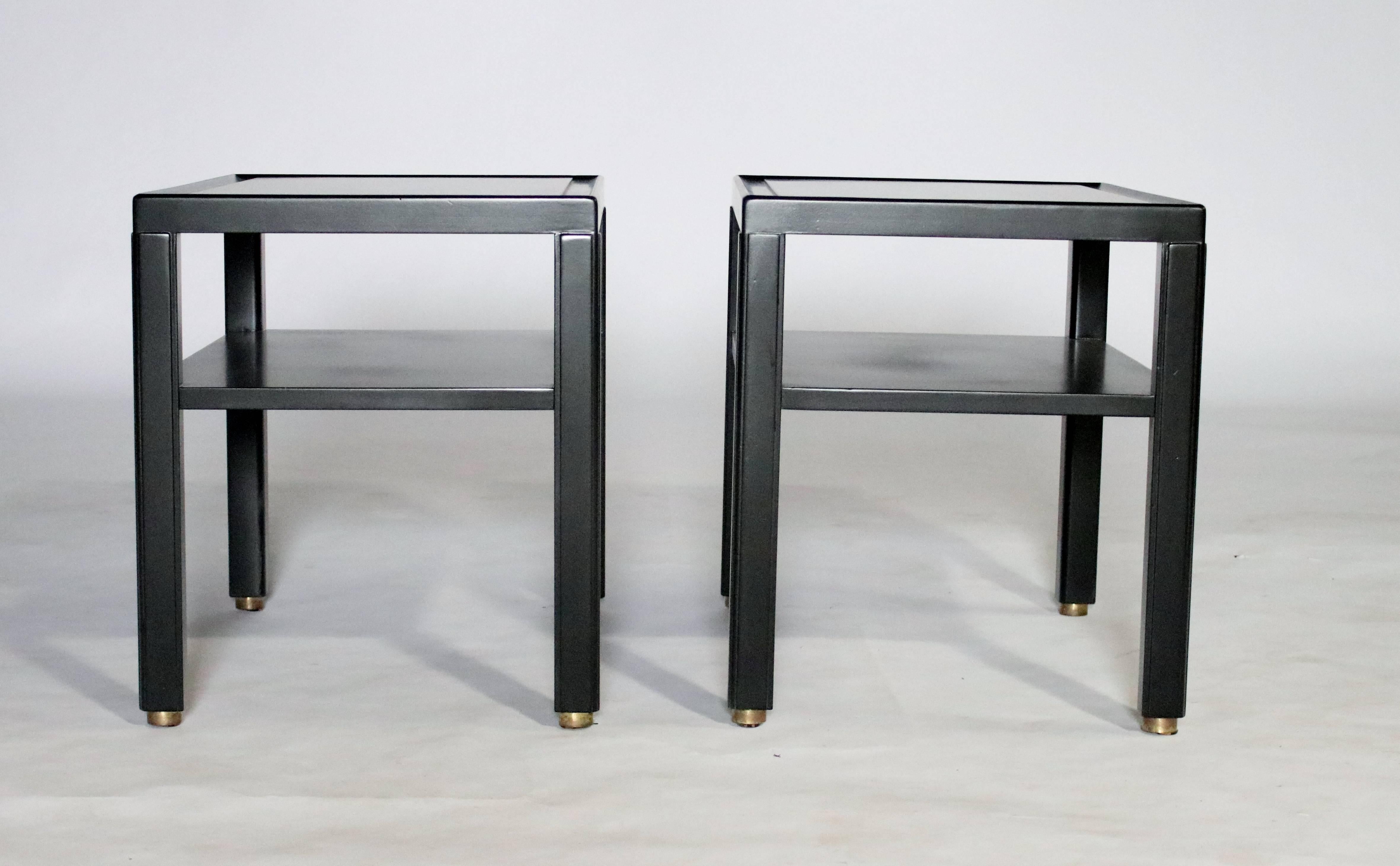 Pair of two-tiered, midcentury mahogany end tables by Edward Wormley for Dunbar newly lacquered in black satin with original brass feet and labels.
