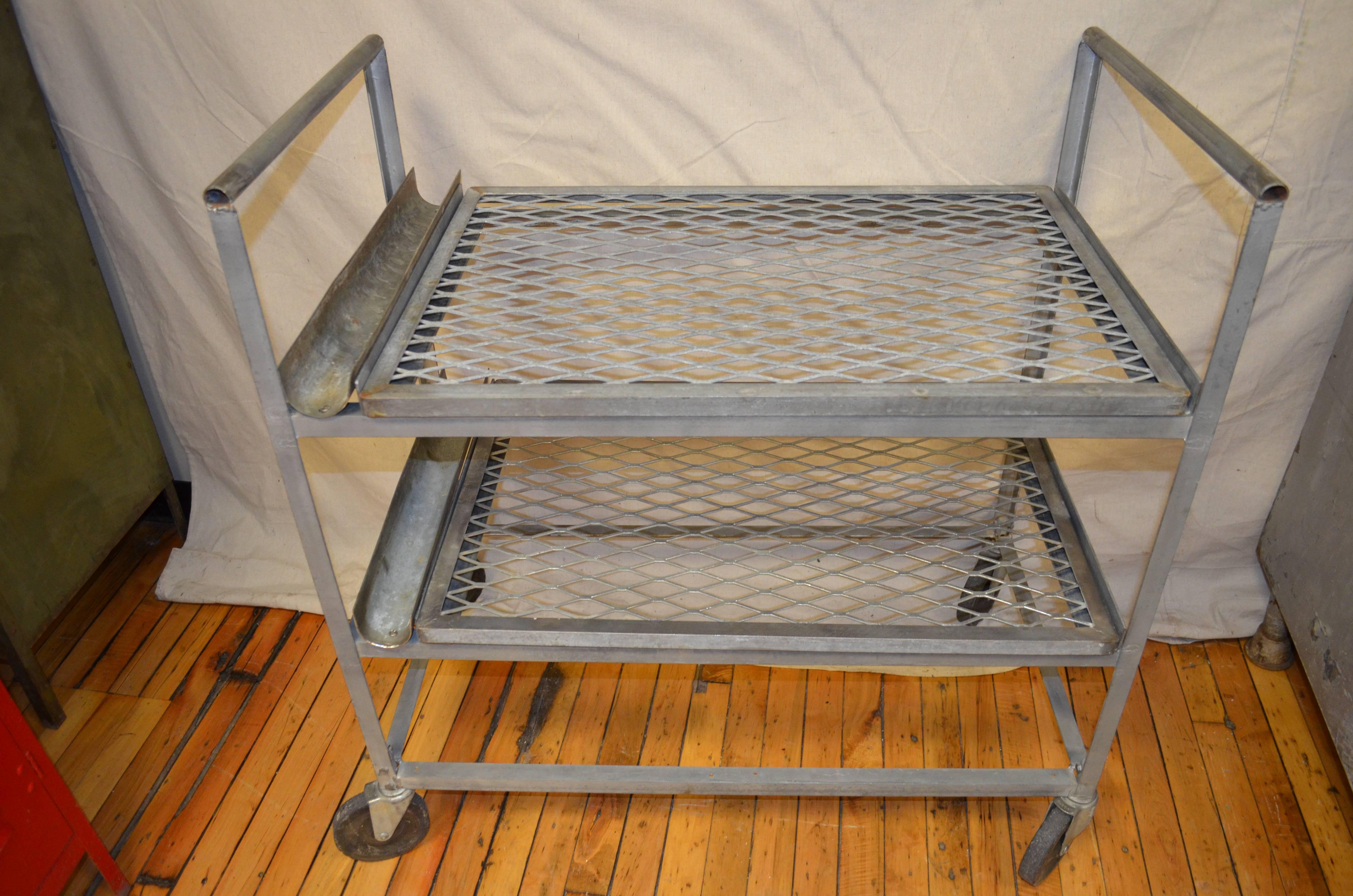 Industrial steel factory cart on wheels with two grated steel shelves. Ideal in the kitchen for small appliances. Neat plant cart, mobile entertainment center.