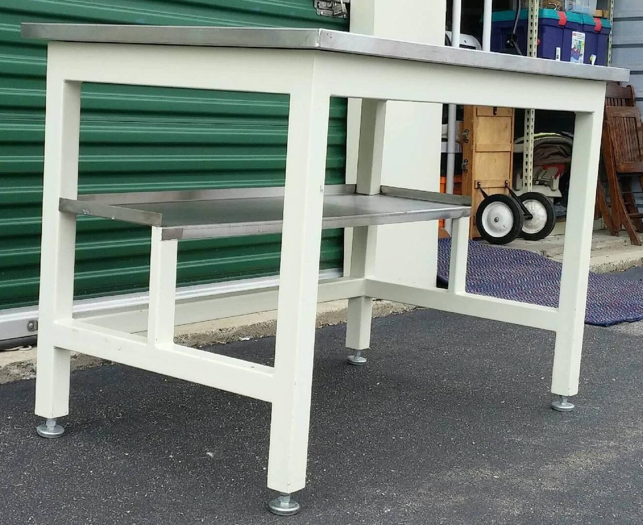 Stainless steel laboratory work tables. Excellent condition. Both feature a shelf below the table. Significant yet modern-Industrial sleek.