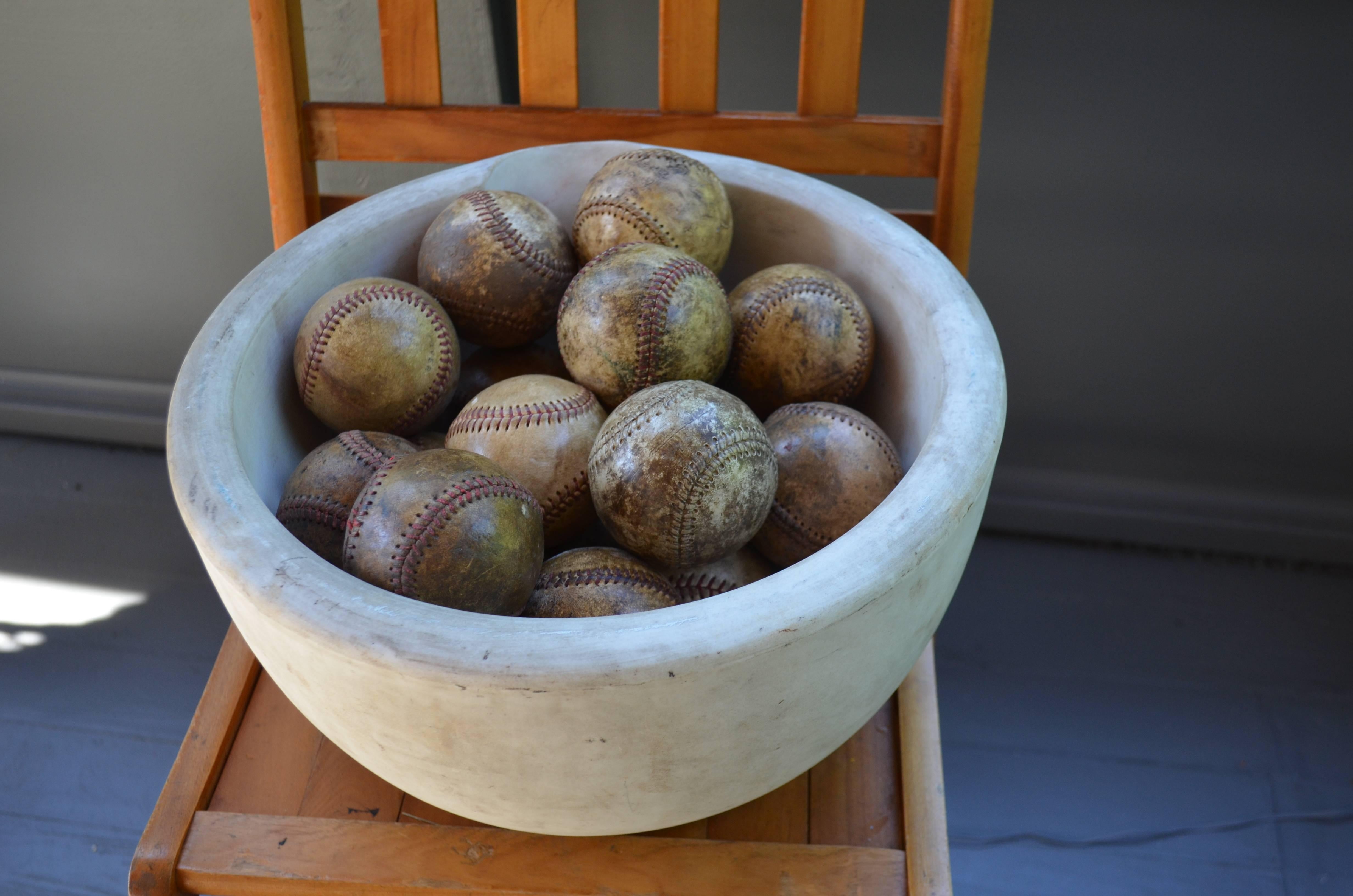 The large-sized antique mortar bowl was found this way home to a group of 18 well-loved, 1960s-era baseballs and so they remain together to display as you see fit or put to further use. Batter up.