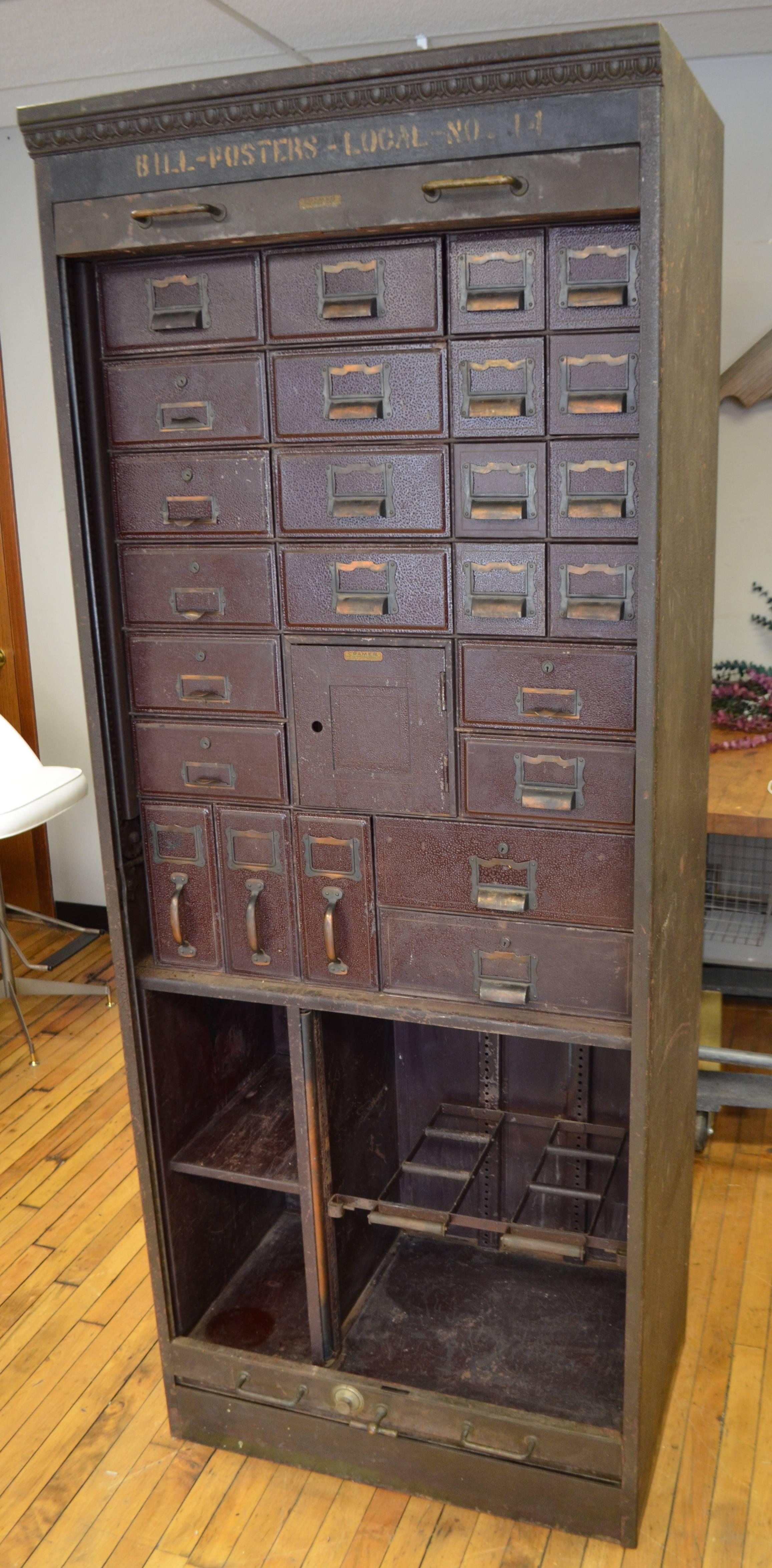 Storage unit hails from a midwestern post office, circa 1930s. An amazing piece containing numerous drawers of varying sizes including those for holding file folders. An inner safe contains three smaller drawers. The security door rolls from top and