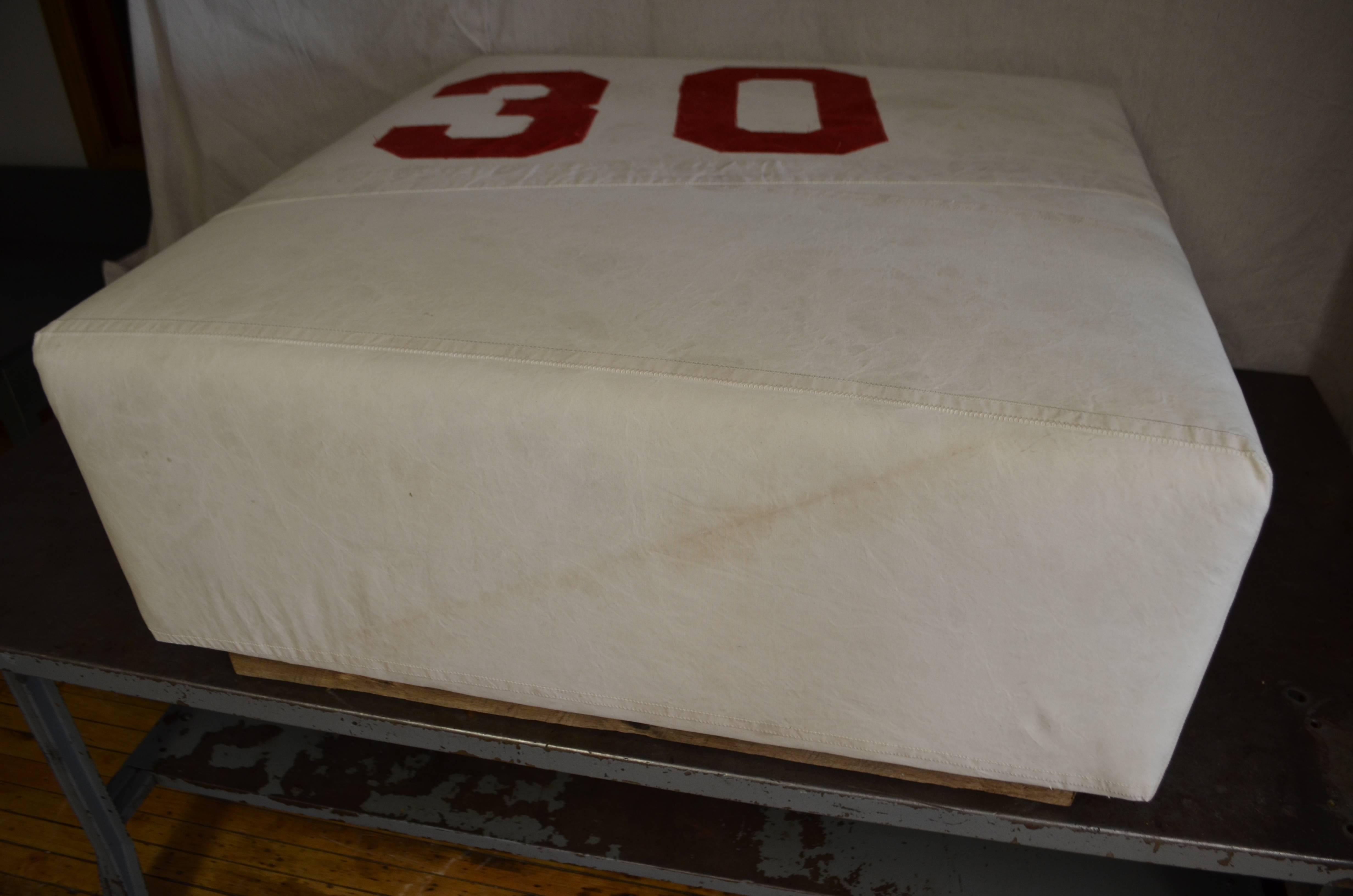 Ottoman upholstered in vintage, cotton canvas sailcloth bearing Number 30. This was an actually racing sail that has been made into an ottoman framed in weathered barn wood. Clearly an ideal gift on that 30th birthday, anniversary, reunion. For that