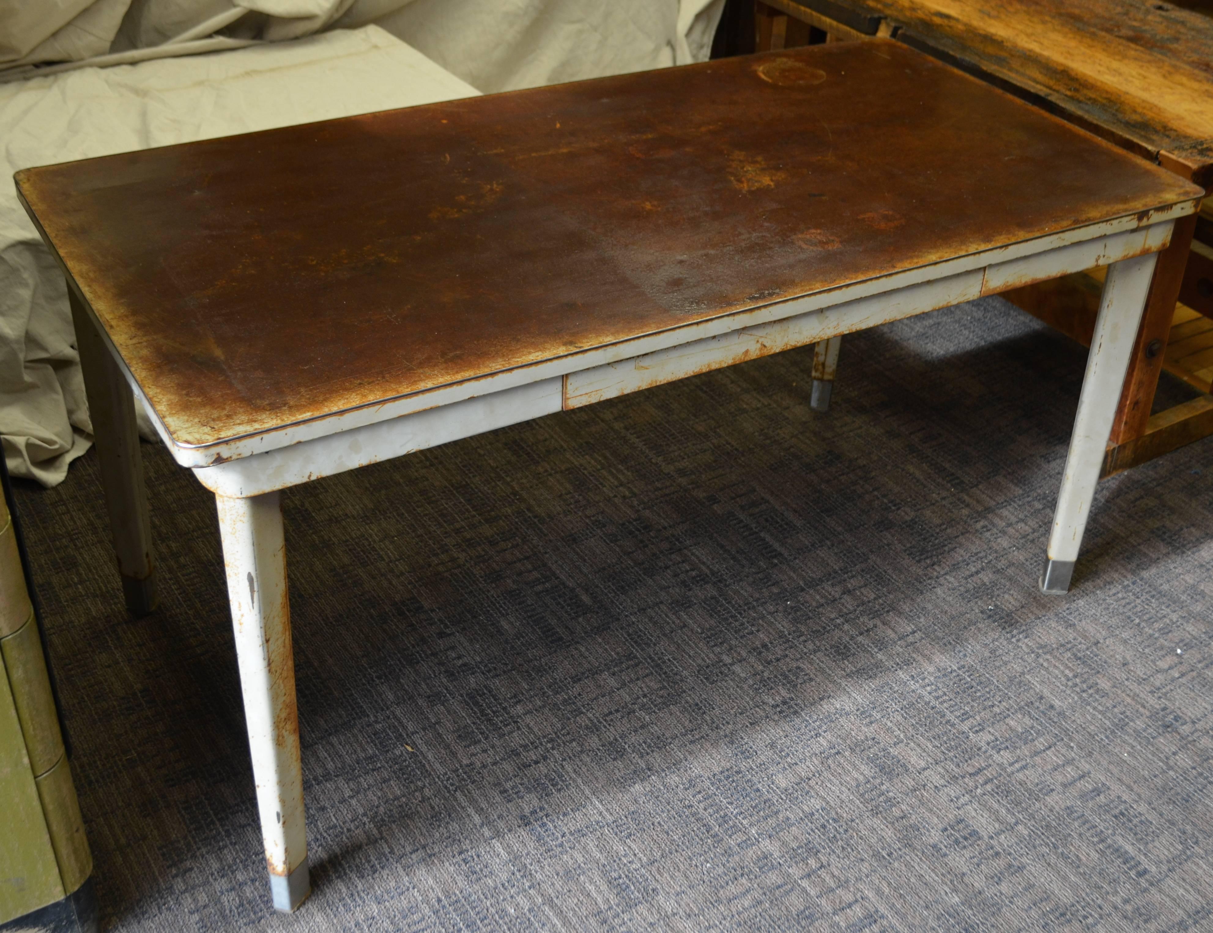 Desk work table has steel top with striking rust patina that has been cleaned and sealed. Ample centre drawer. Mid-century. Floor to start of drop is 27 inches.