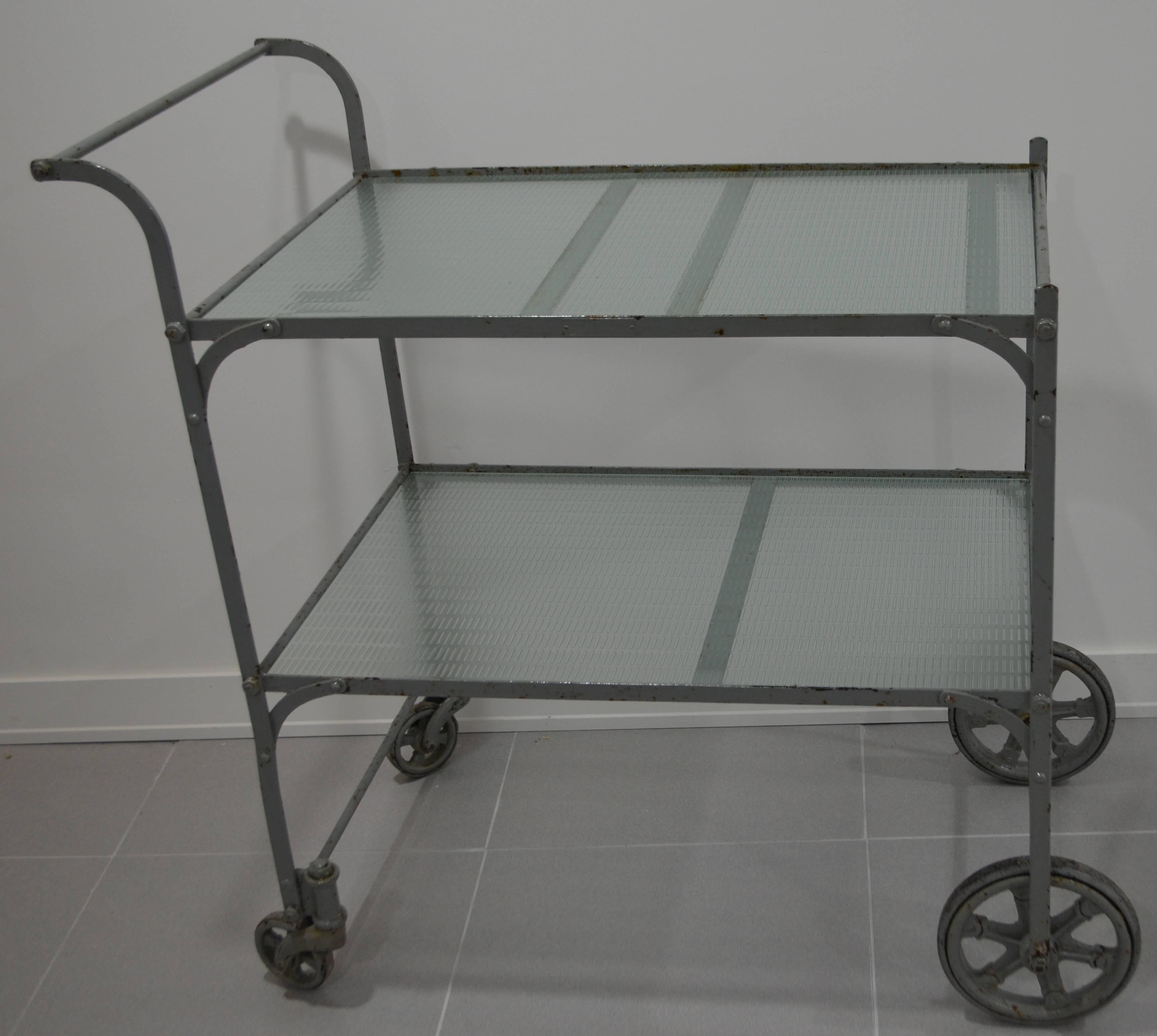 Tea cart with painted steel frame and two shelves of rippled glass top. Rear wheels pivot nicely for easy maneuverability. Love those early baby carriage wheels. Great for plants. Funky Downtown.