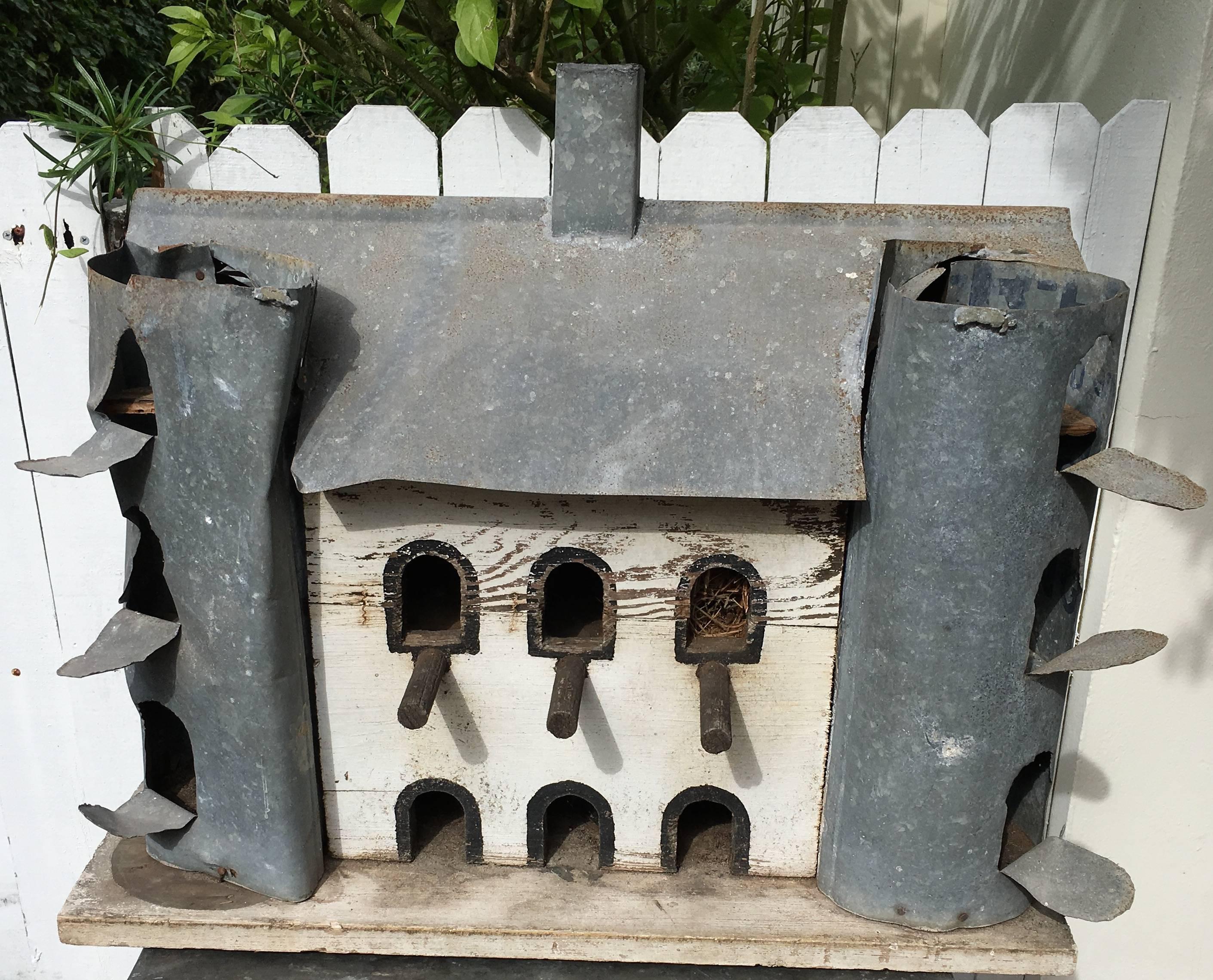 Birdhouse for Purple Martins in the form of a wooden barn with galvanized steel silos, roof and chimney. Straw from last-used nest is still in situ within barn. See upper right-hand window in photo image 6.