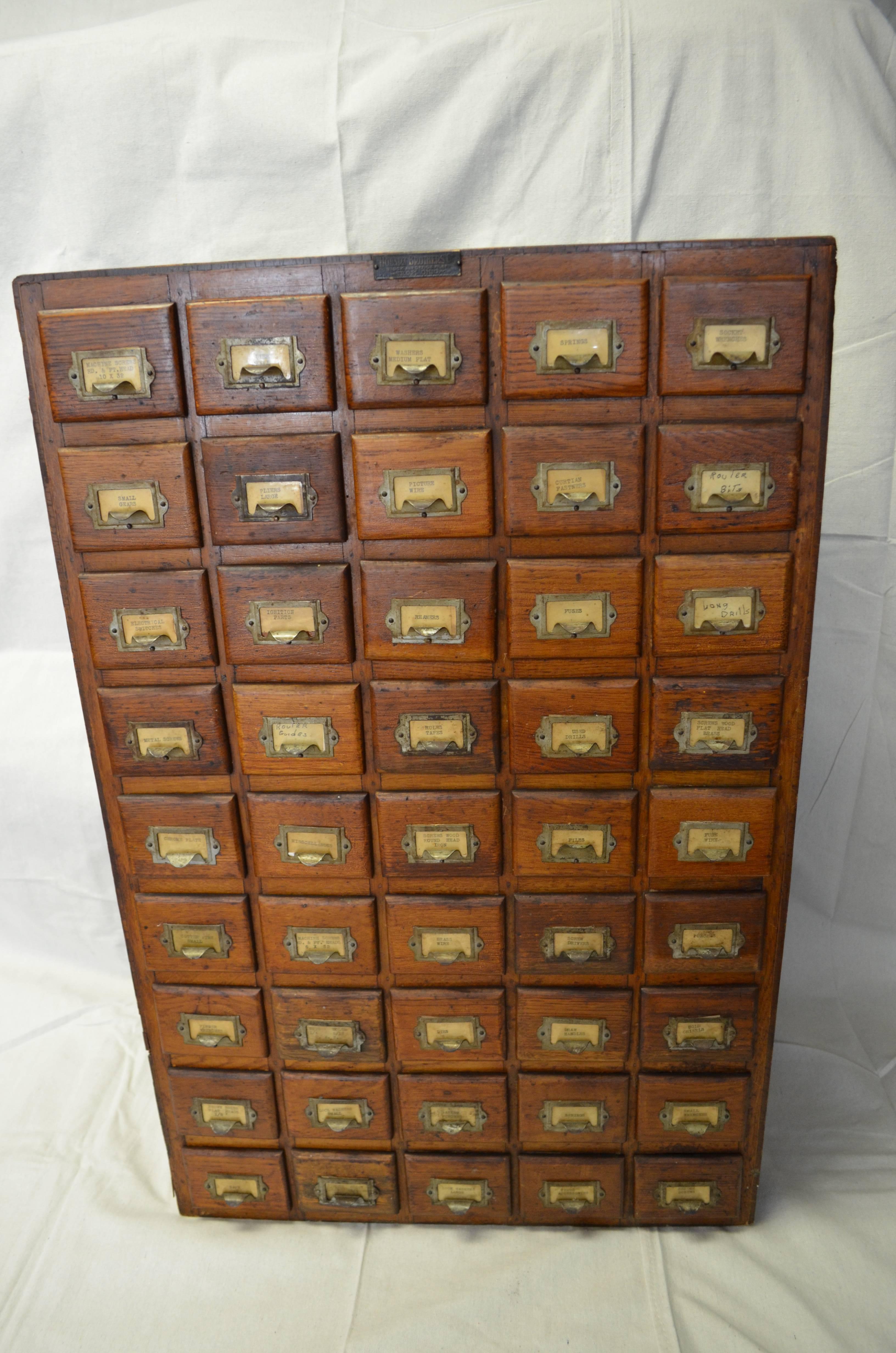 Storage cabinet from midwestern hardware store features 45 tin drawers with brass pulls and oak fronts. Each drawer measures 9