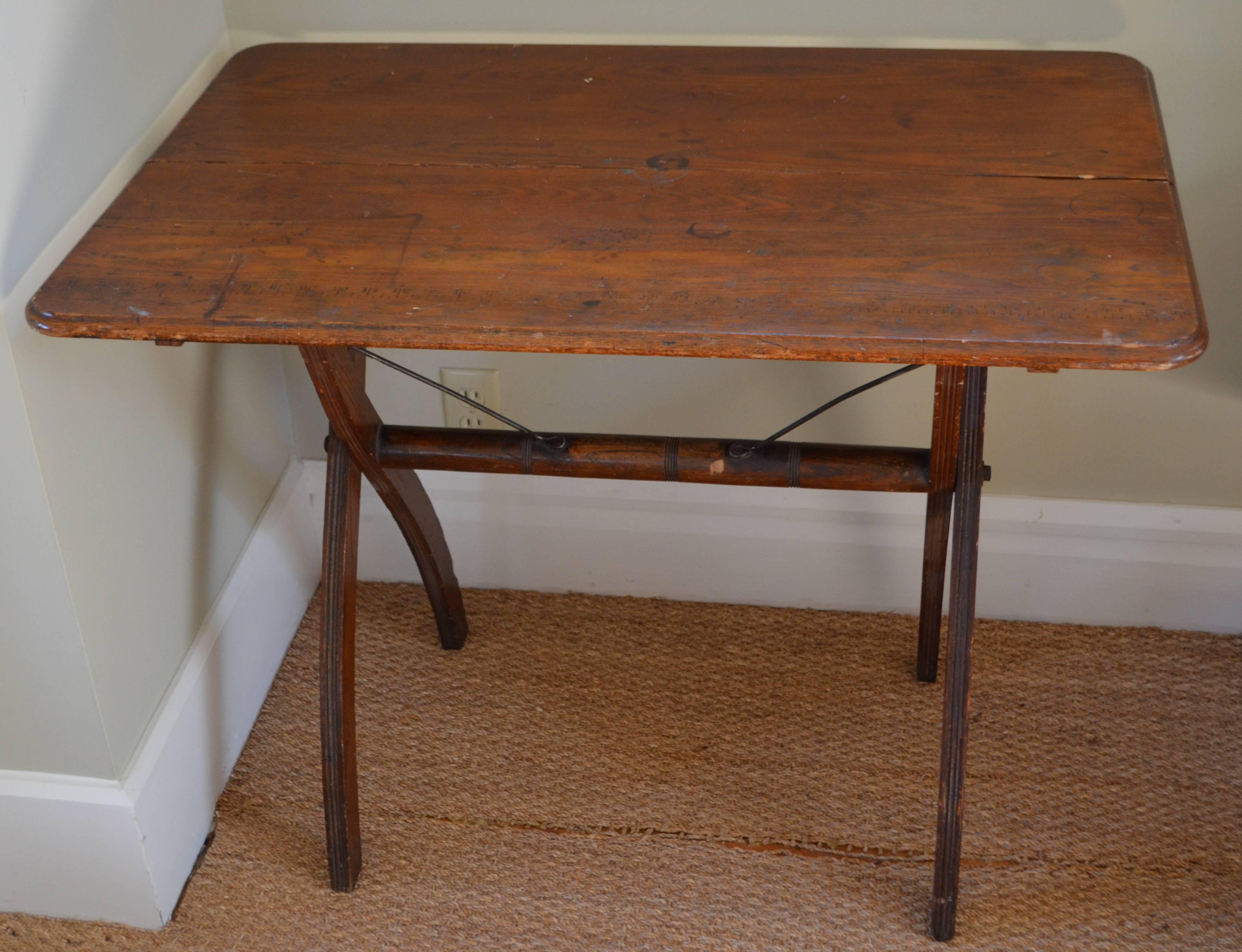 Wooden sewing/folding table of pine with curved corners and scissor legs, early 1900s. Originally used as a sewing table with measurement numbers along one edge. Ideal as end table with lamp, for writing in the study, for hall and entranceway