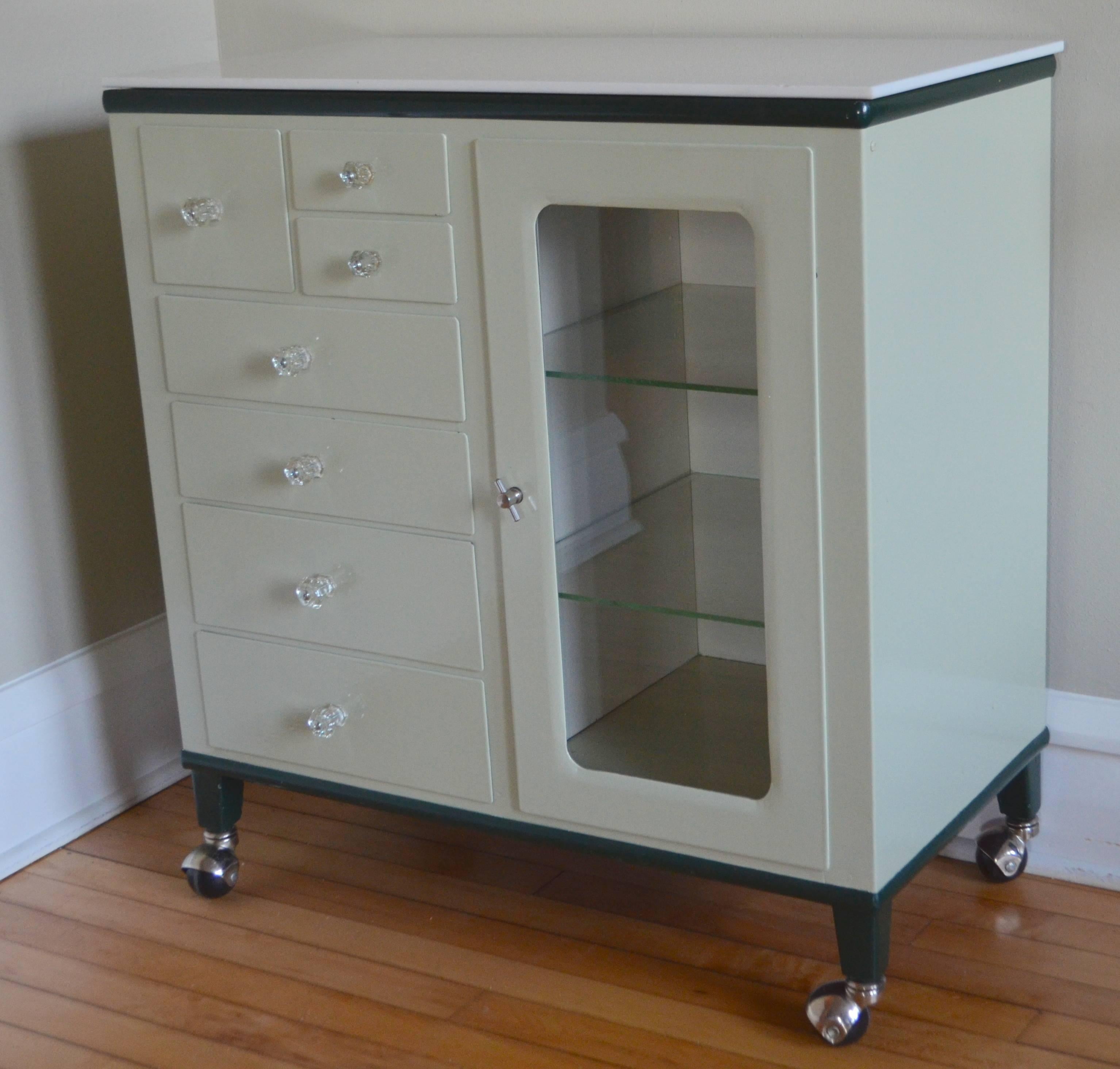 Midcentury dental cabinet. Sweet piece, immaculate condition except for slight chip in milk glass top. All original except for the wheels that were added subsequently.