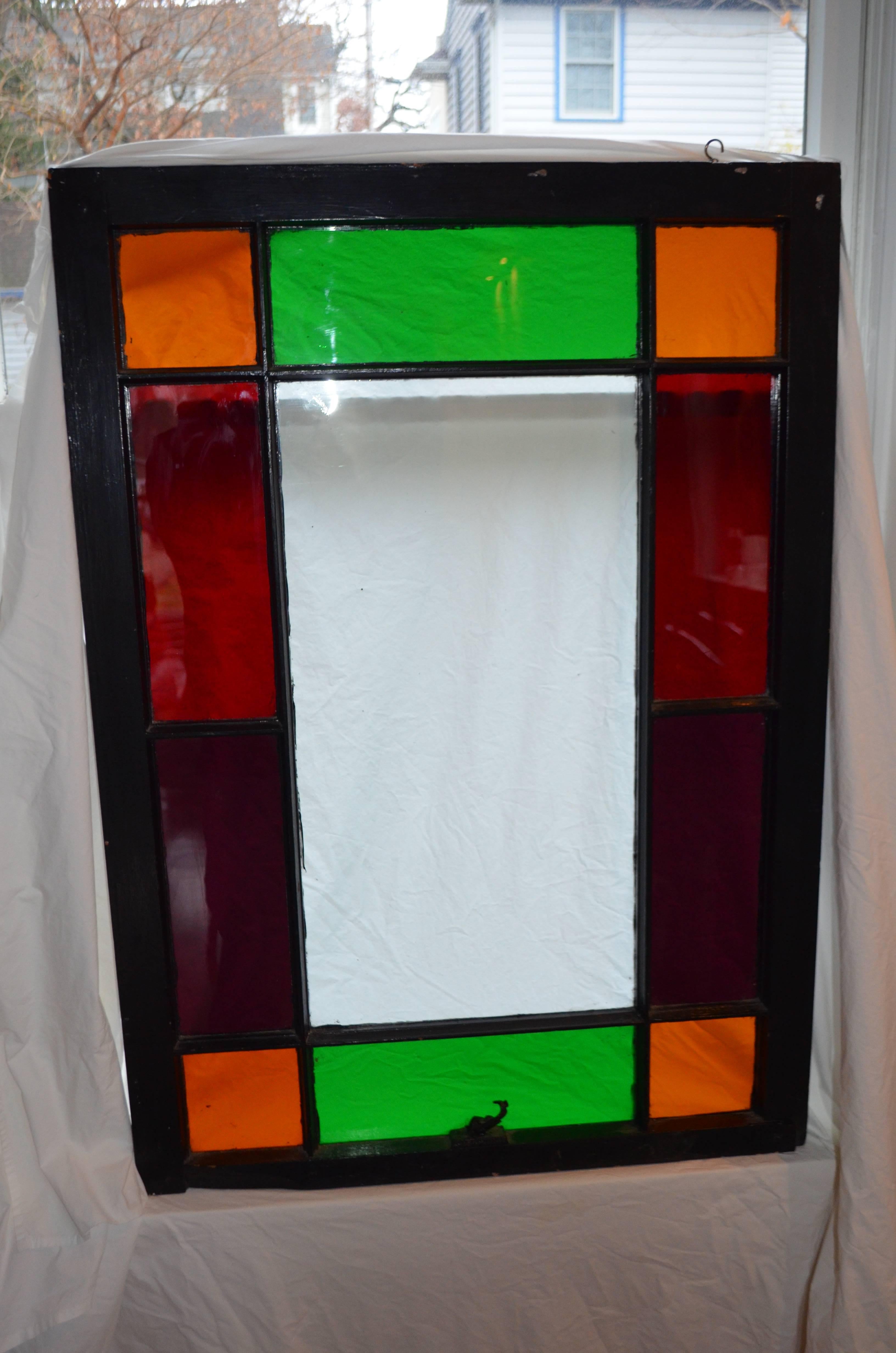 Stained glass window, once part of a double-hung set, now brings rich, vibrant colors into the home, enriching even the greyest of days. There's an Arts and Crafts quality to the colored panes and the way they are displayed. Mounted with hooks and