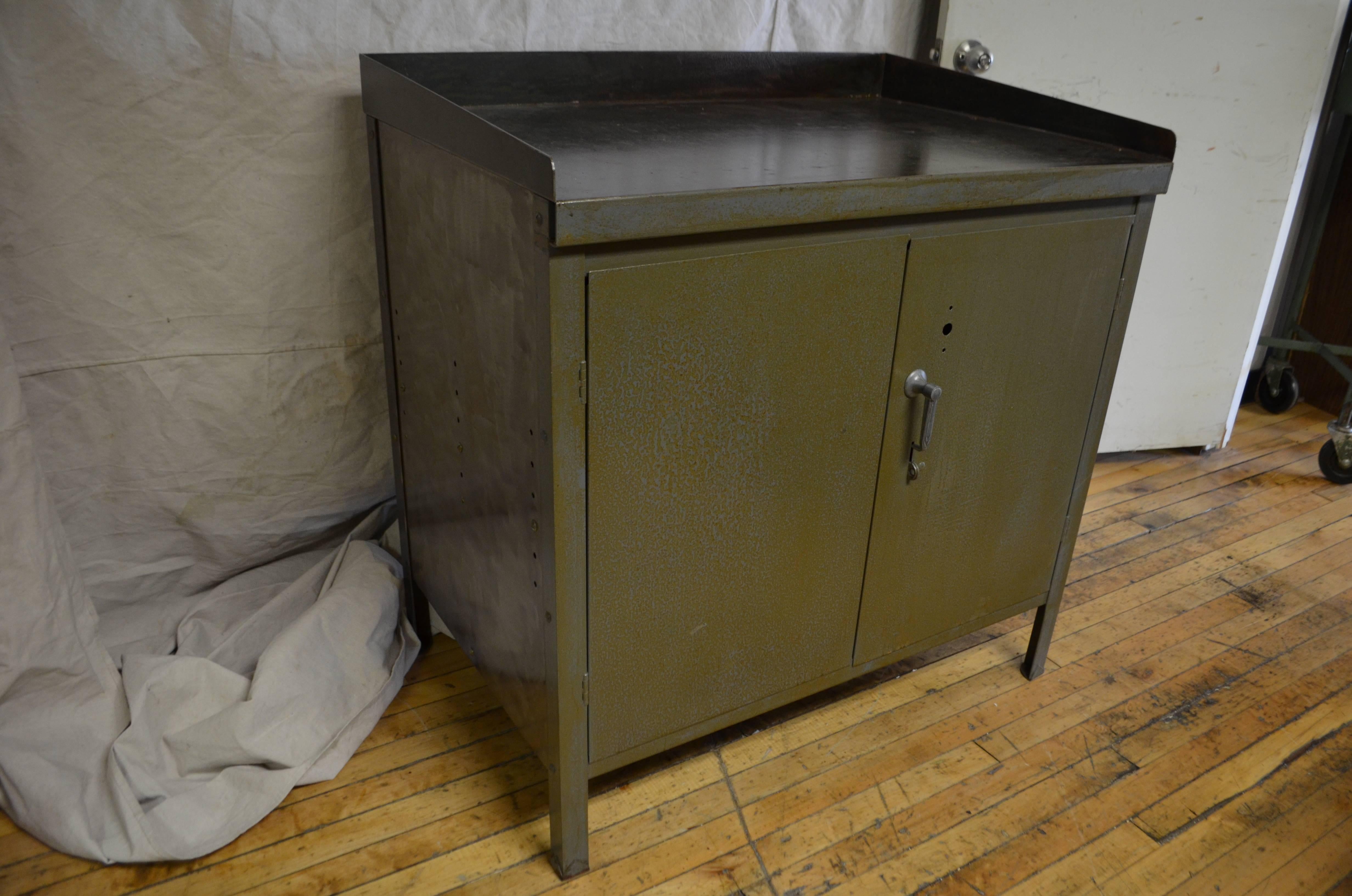 Industrial steel cabinet with two doors and two shelves within. Cleaned and sealed, leaving rust spots intact as character patina. Love that factory green with brown undertones. Note different colored paint on back and unpainted side. Quite the