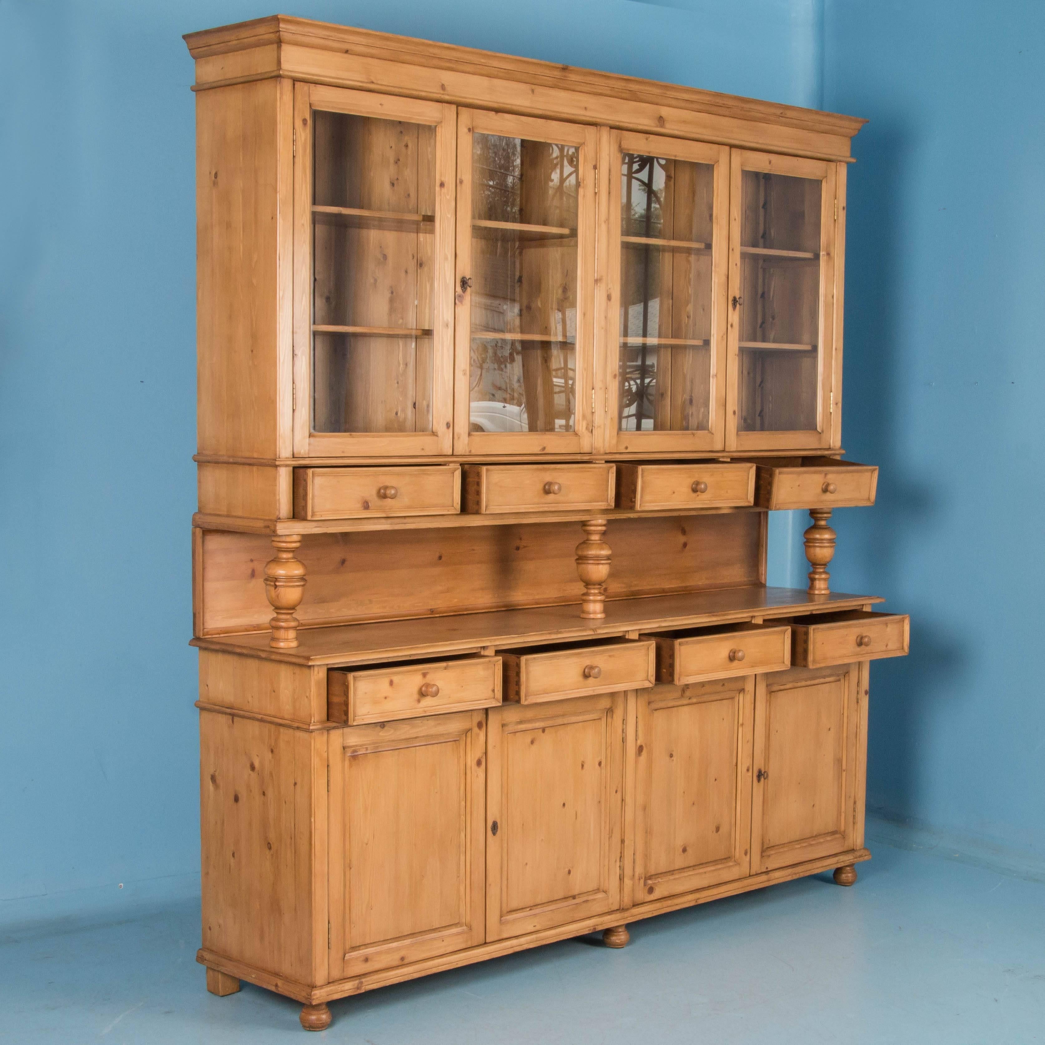 This striking large pine bookcase or display wall unit was newly custom-made in England and breaks down into two large cabinets. The pine has a warm, inviting patina thanks to a satin wax finish and has a strong country appeal. The upper display