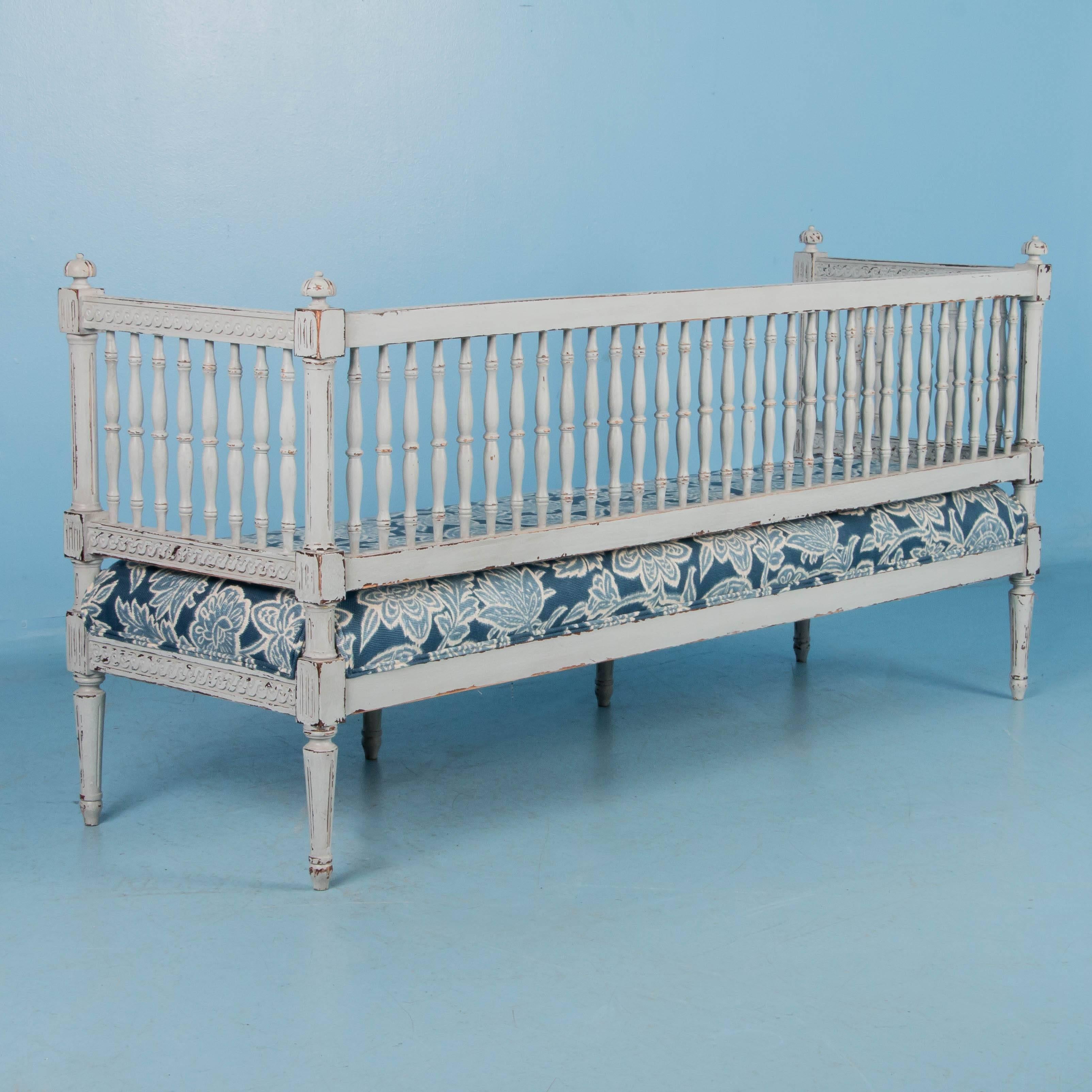 The lovely, soft colors of the Gustavian period are well displayed in this exquisite bench. Where the new light gray painted finish is worn away, the darker natural wood comes through, enhancing the exceptionally carved apron and rails of this