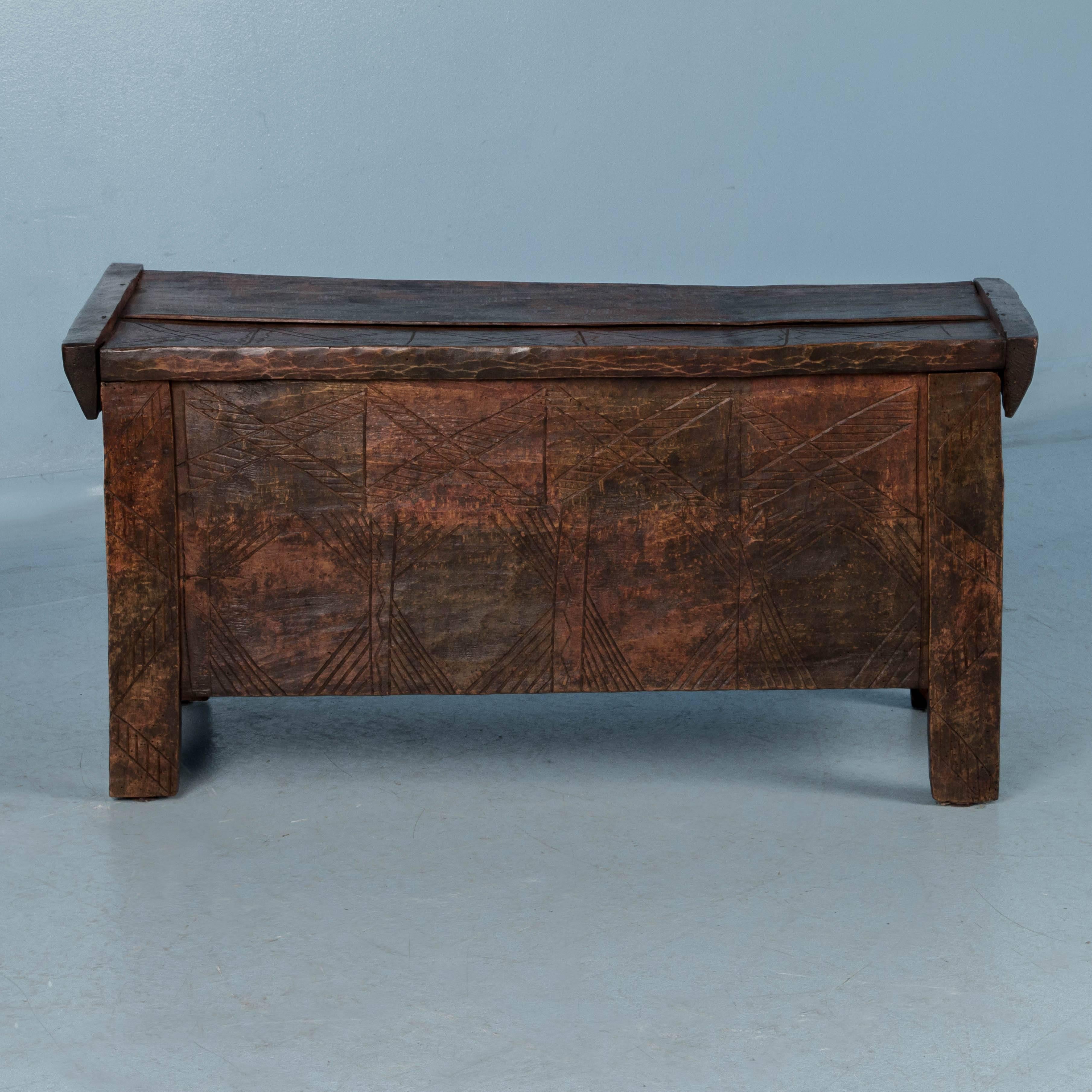 The top and front of this interesting trunk are carved with geometric cross hatch patterns, appearing etched into the wood and adding to the rustic, country feel. The chest has a slightly domed hinged top, which opens to a generous storage space