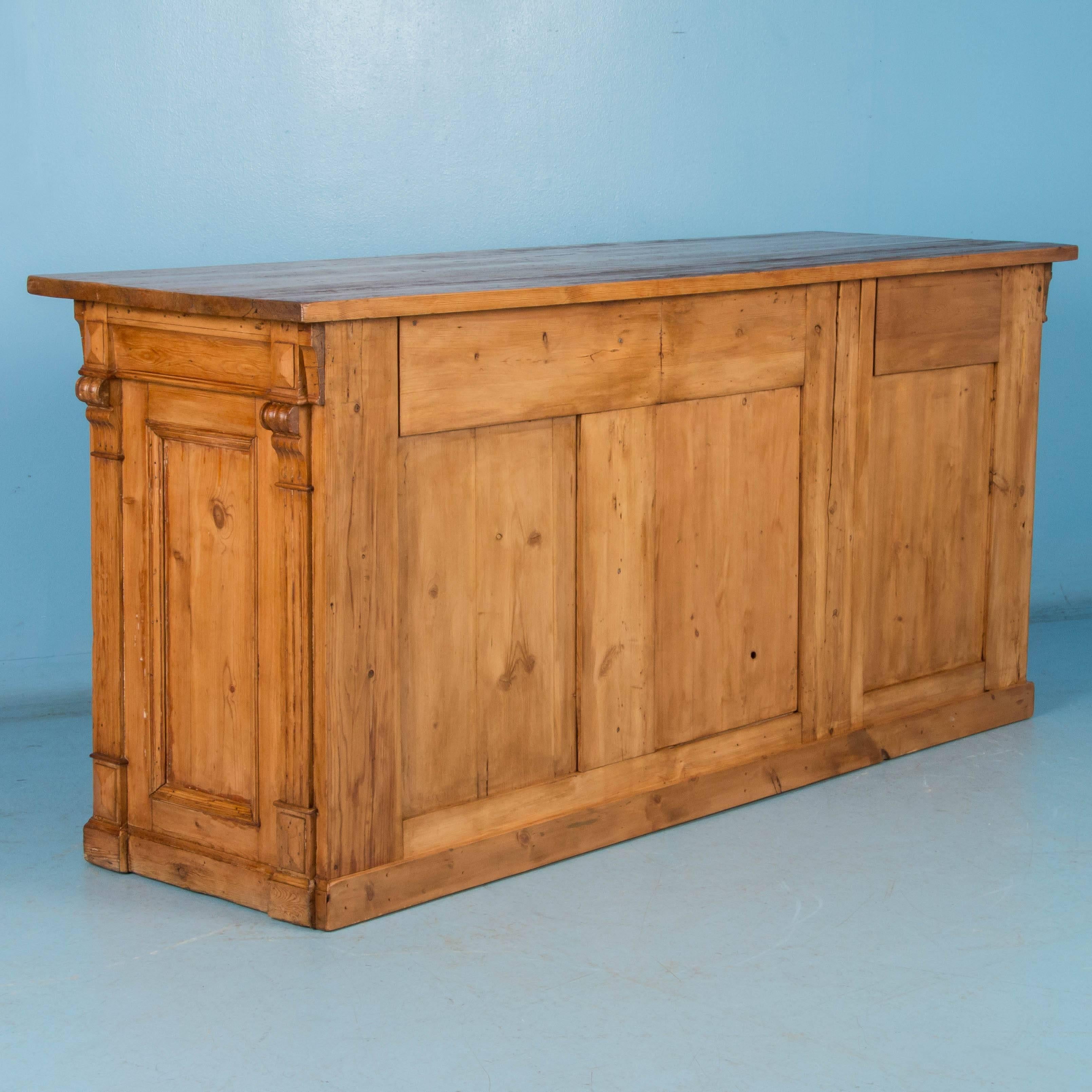 A rare find, this 19th century grocer's store counter is as versatile as it is unusual. The cabinet is made of pine with a rich, time worn patina. On either side of the unique 35 bottle wine rack is a series of large and small drawers. This is a