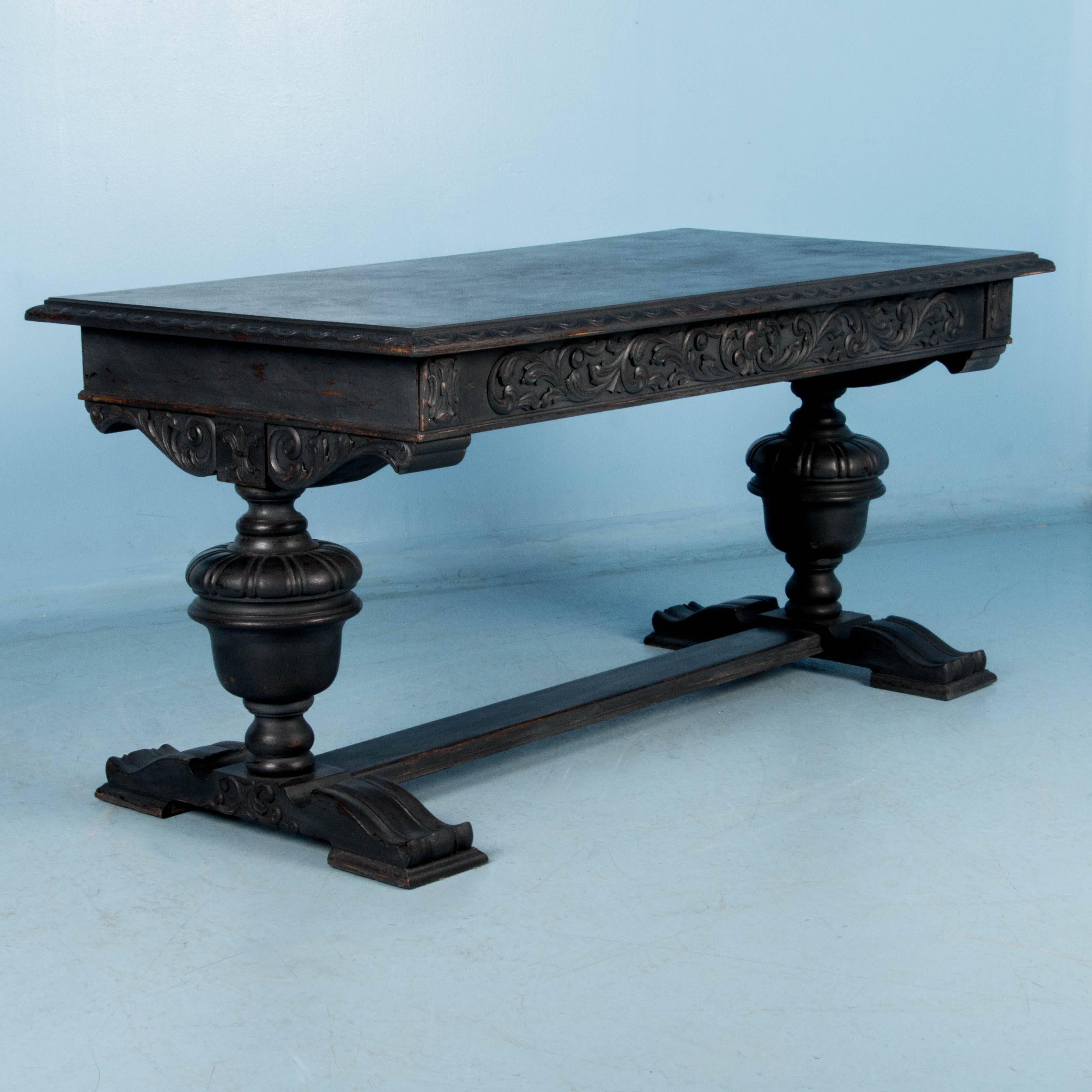 The black distressed chalk paint finish creates a texture that accentuates the style of this late 19th century library table with urn shaped legs and broad padded feet. Note how the lightly distressed paint exposes the dark rich wood beneath,