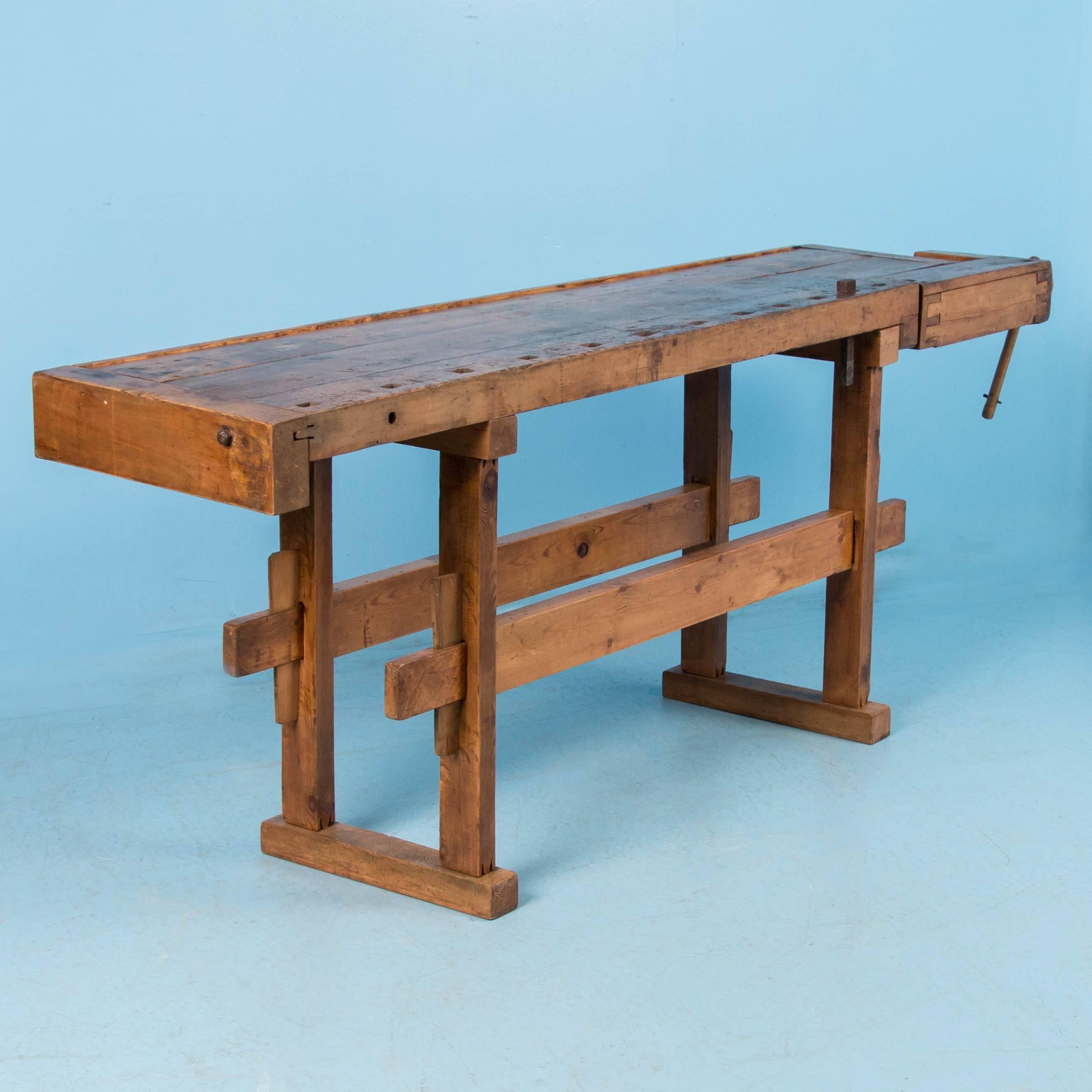 Beautiful antique carpenters’ workbench circa 1890, bearing an incredible patina after years of traditional use. It has a single wood handled vice with continuous narrow tabletop and comes with a traditional trestle base that allows it to be