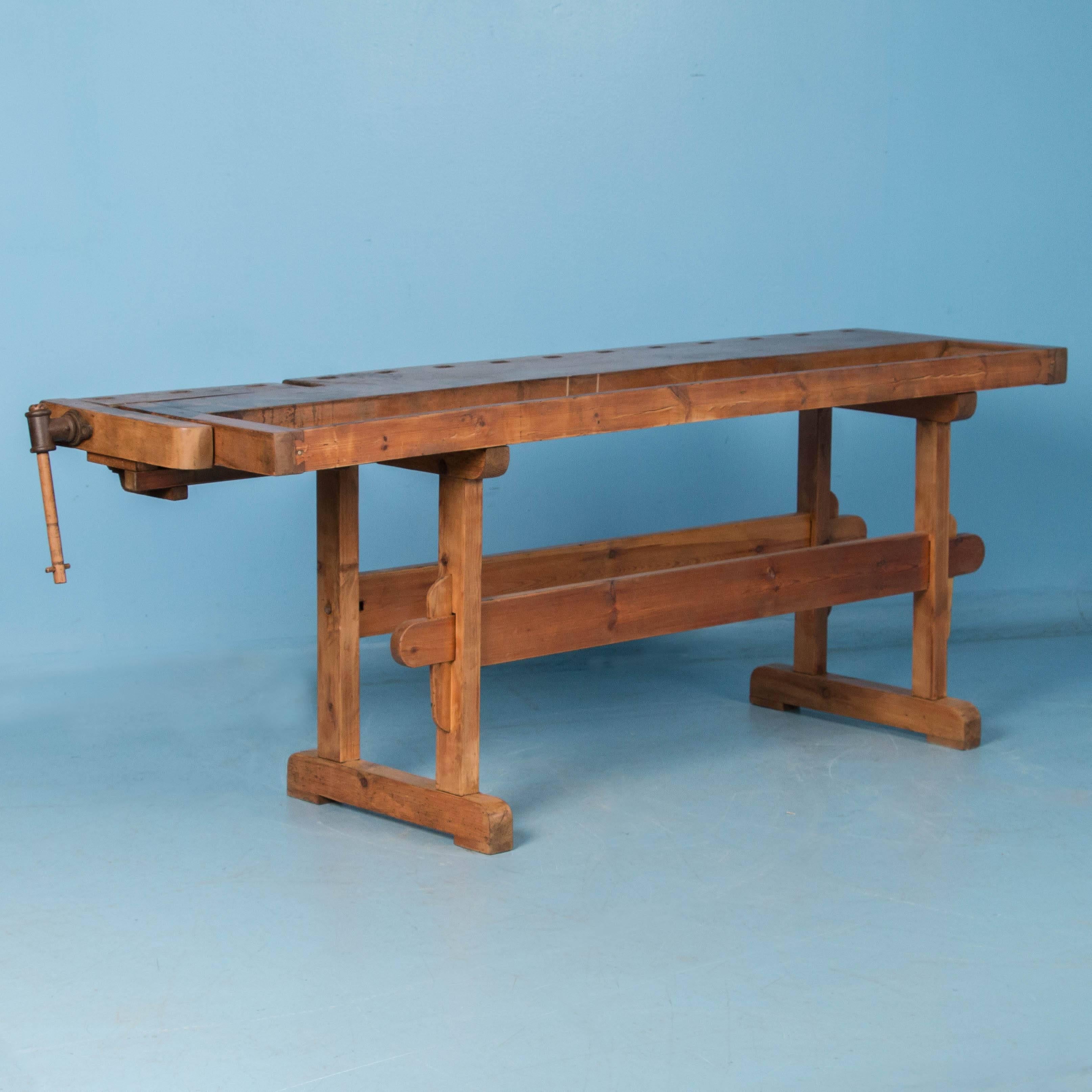 The wonderful wear and distressed wood add to the appeal of this circa 1900 workbench which features a working end vise and the original tool trough. The top is detachable and comes with a traditional trestle base that allows it to be assembled and